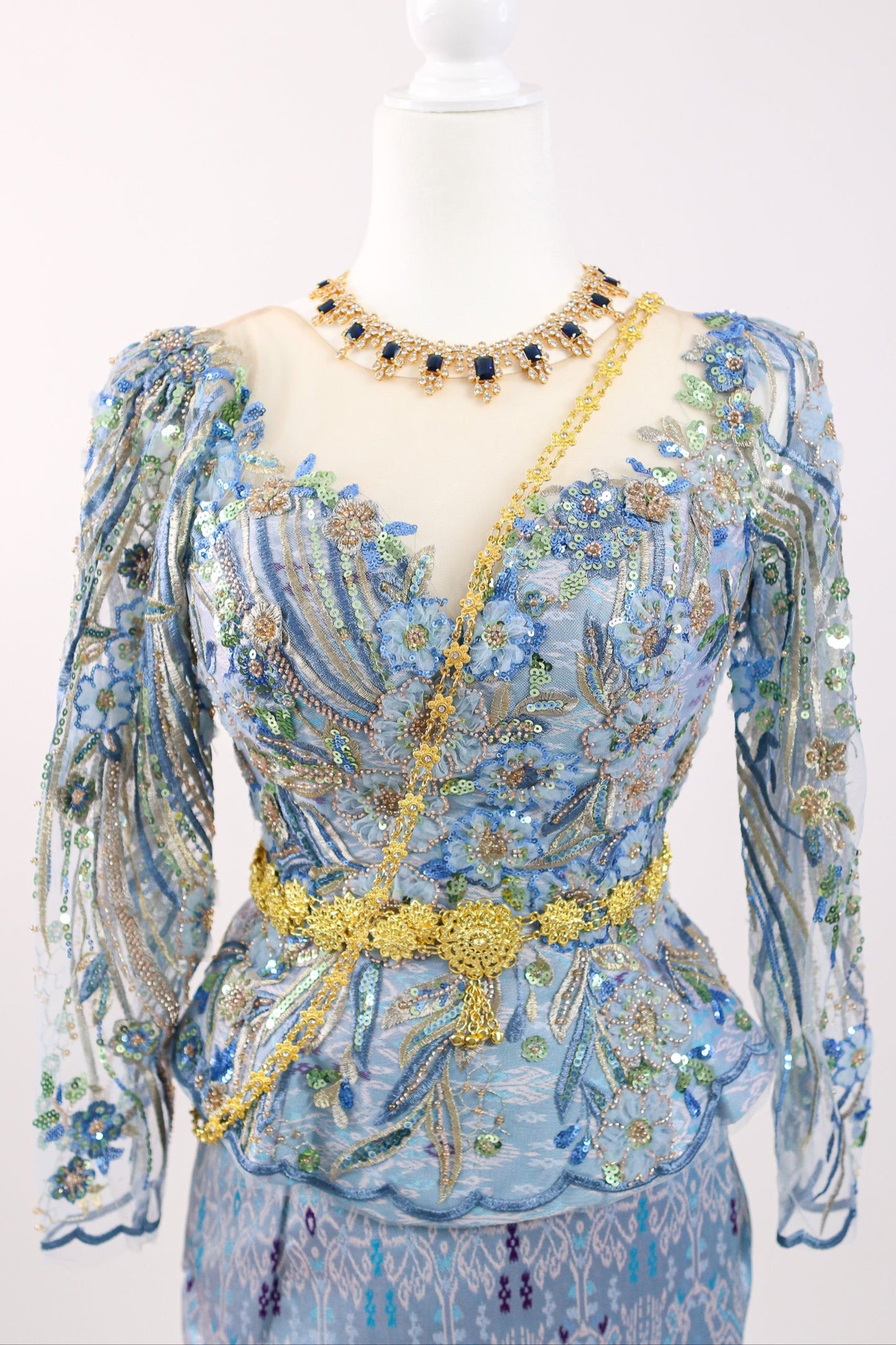 Mannequin wearing a blue floral dress with gold accents on a white background