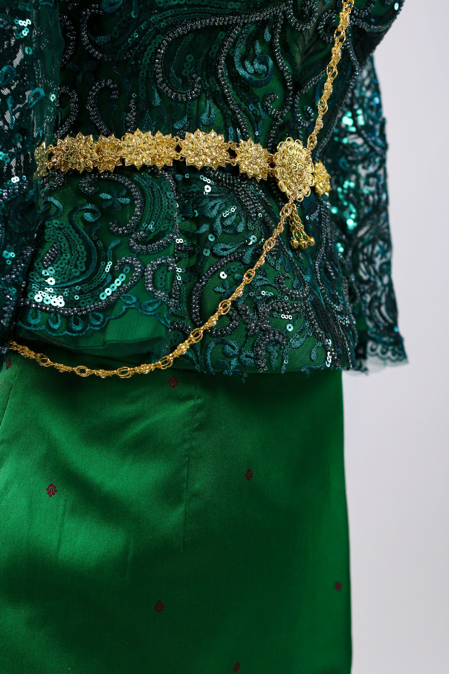 Green embroidered garment with gold accents on a white background