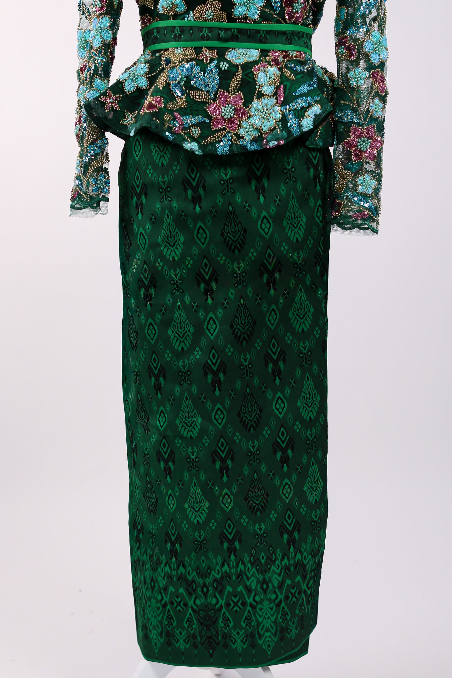 Green patterned dress with floral embellishments on a white background