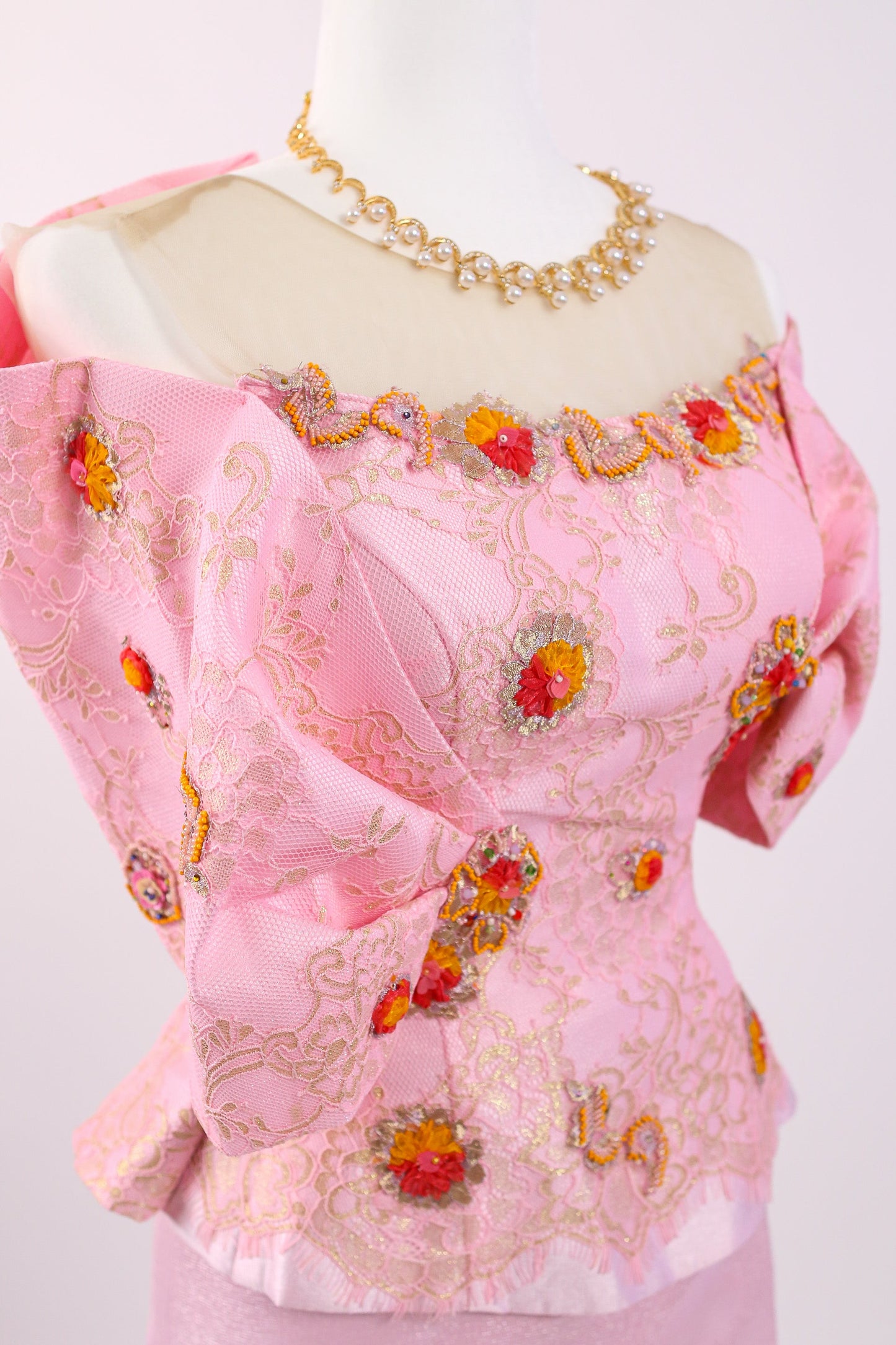Pink embroidered blouse on a mannequin with a white background