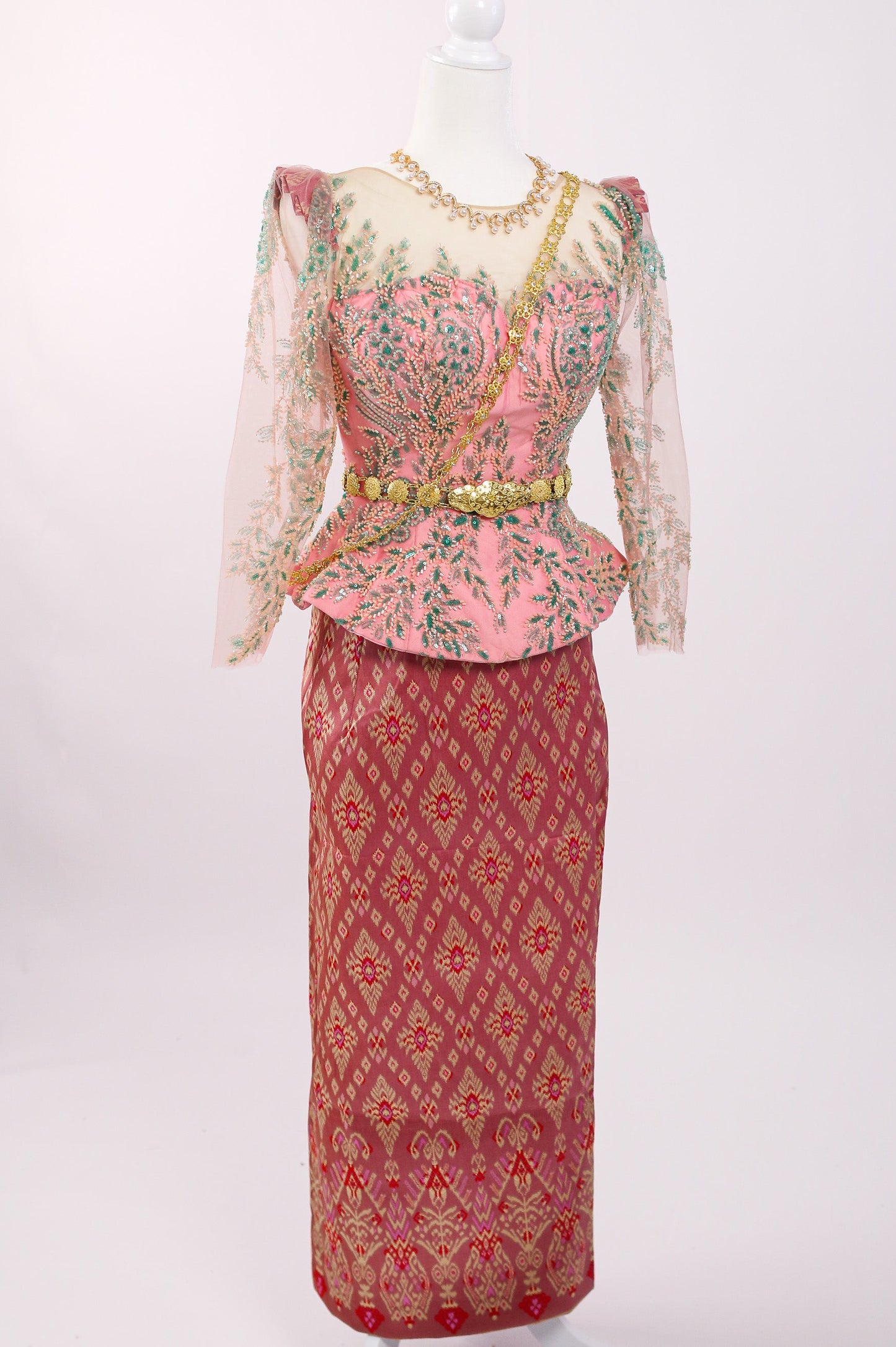 Traditional outfit with a pink top and red skirt on a mannequin against a white background