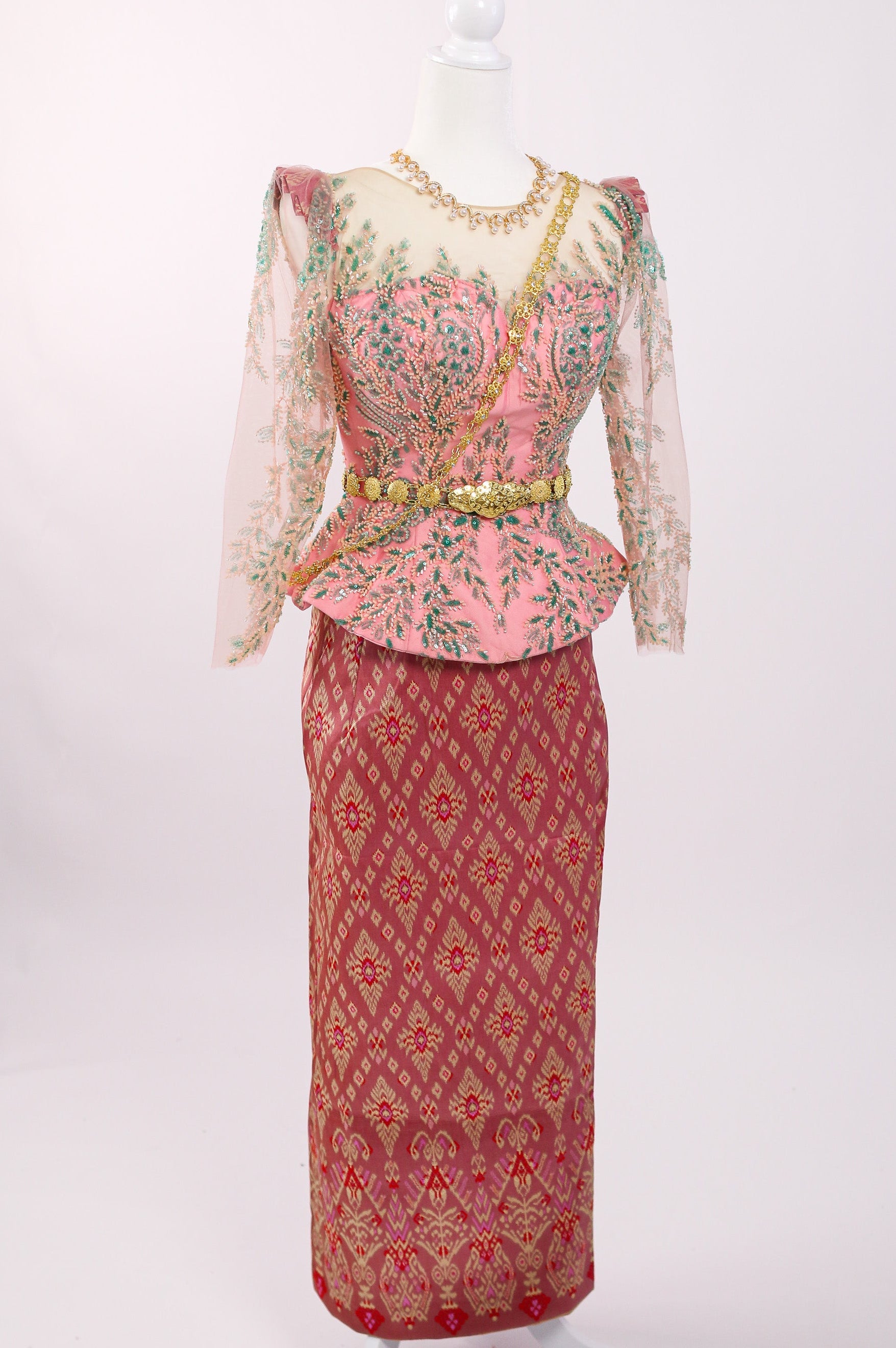 Traditional outfit with a pink top and red skirt on a mannequin against a white background