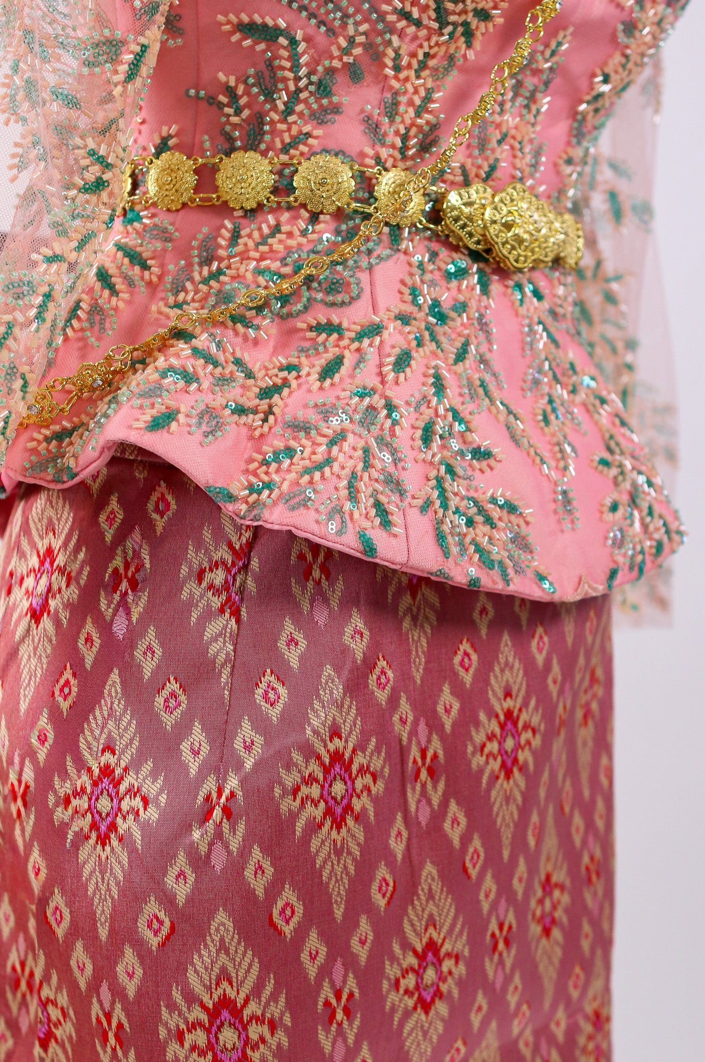Traditional pink and gold embroidered outfit with a patterned skirt on a white background