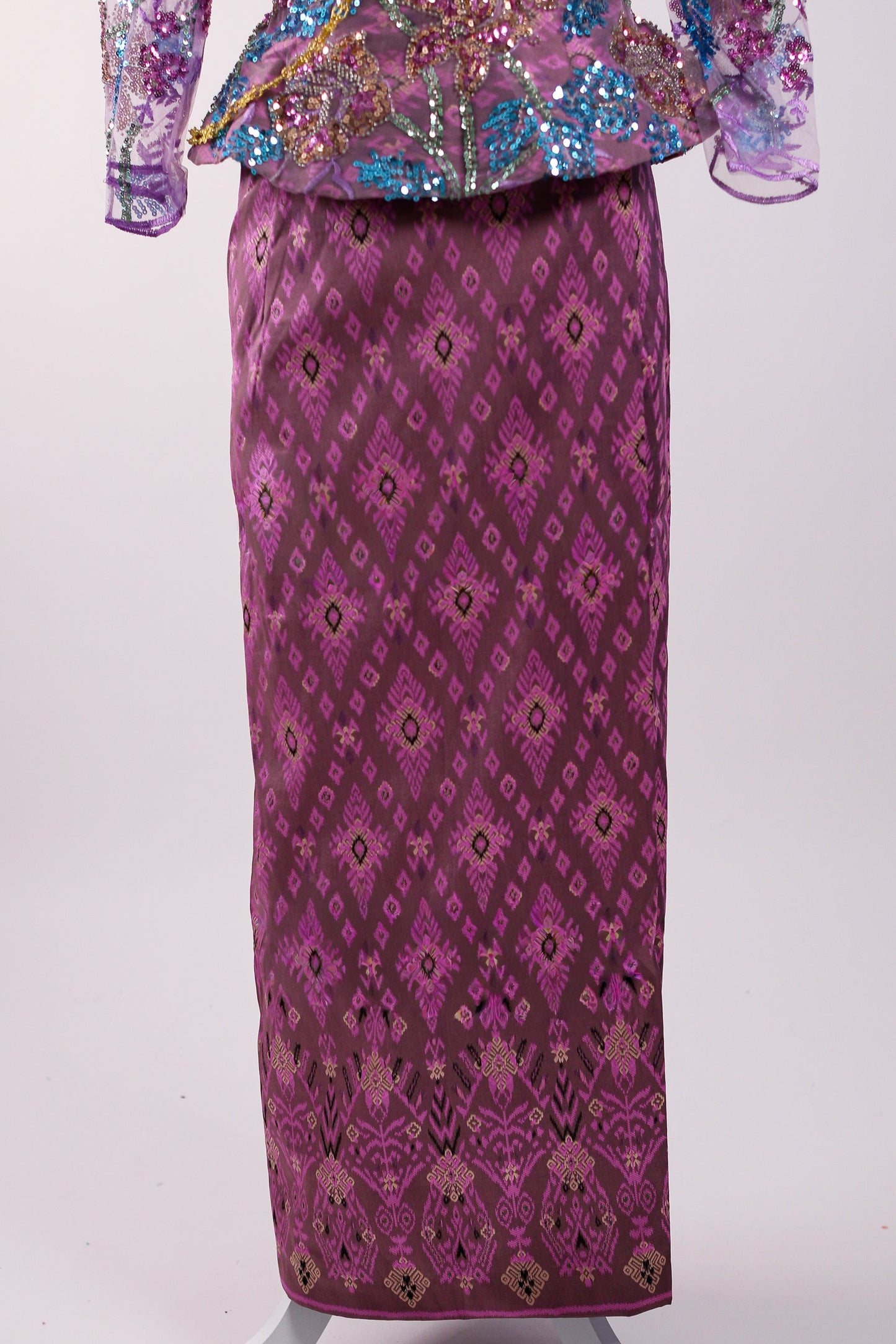 Traditional outfit with a sequined top and patterned skirt on a white background