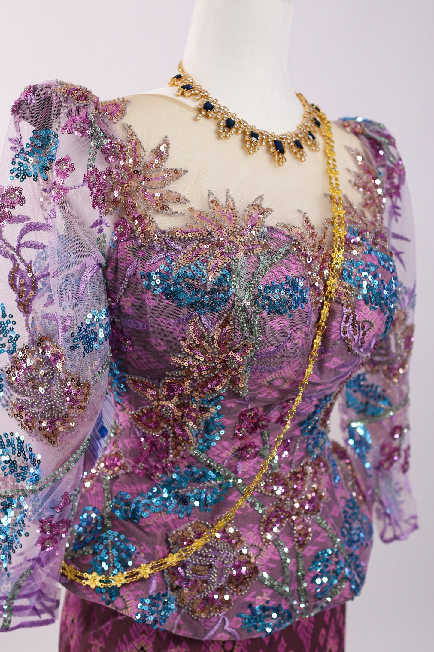 Mannequin wearing a vibrant, sequined top with floral patterns on a white background