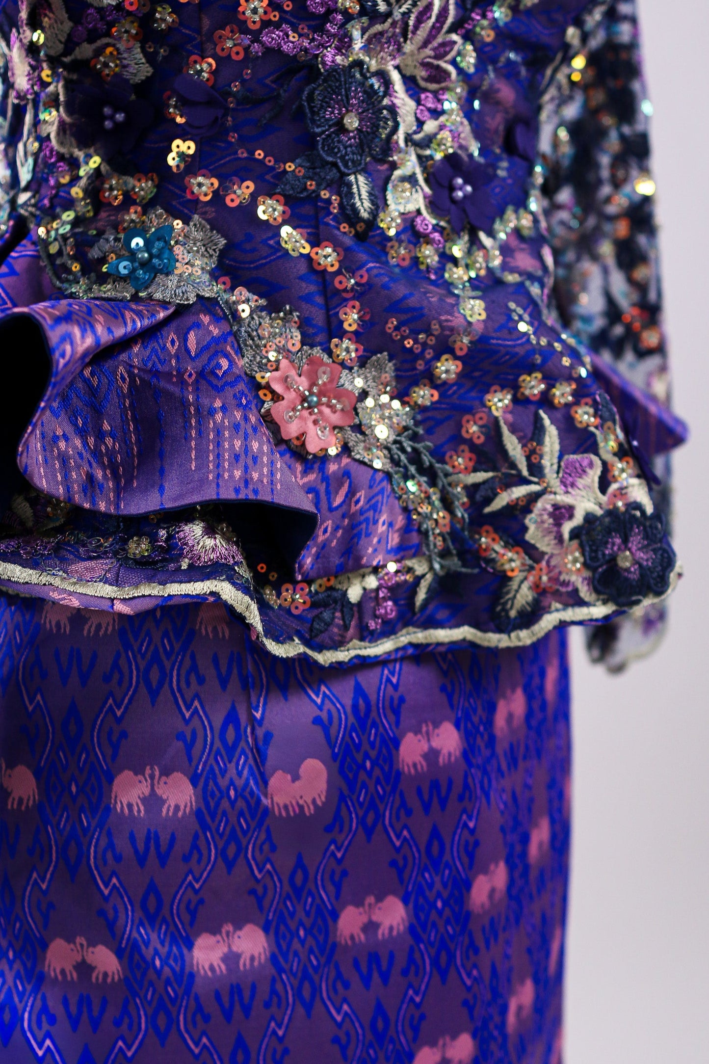 Close-up of a blue embroidered garment with intricate patterns on a plain background