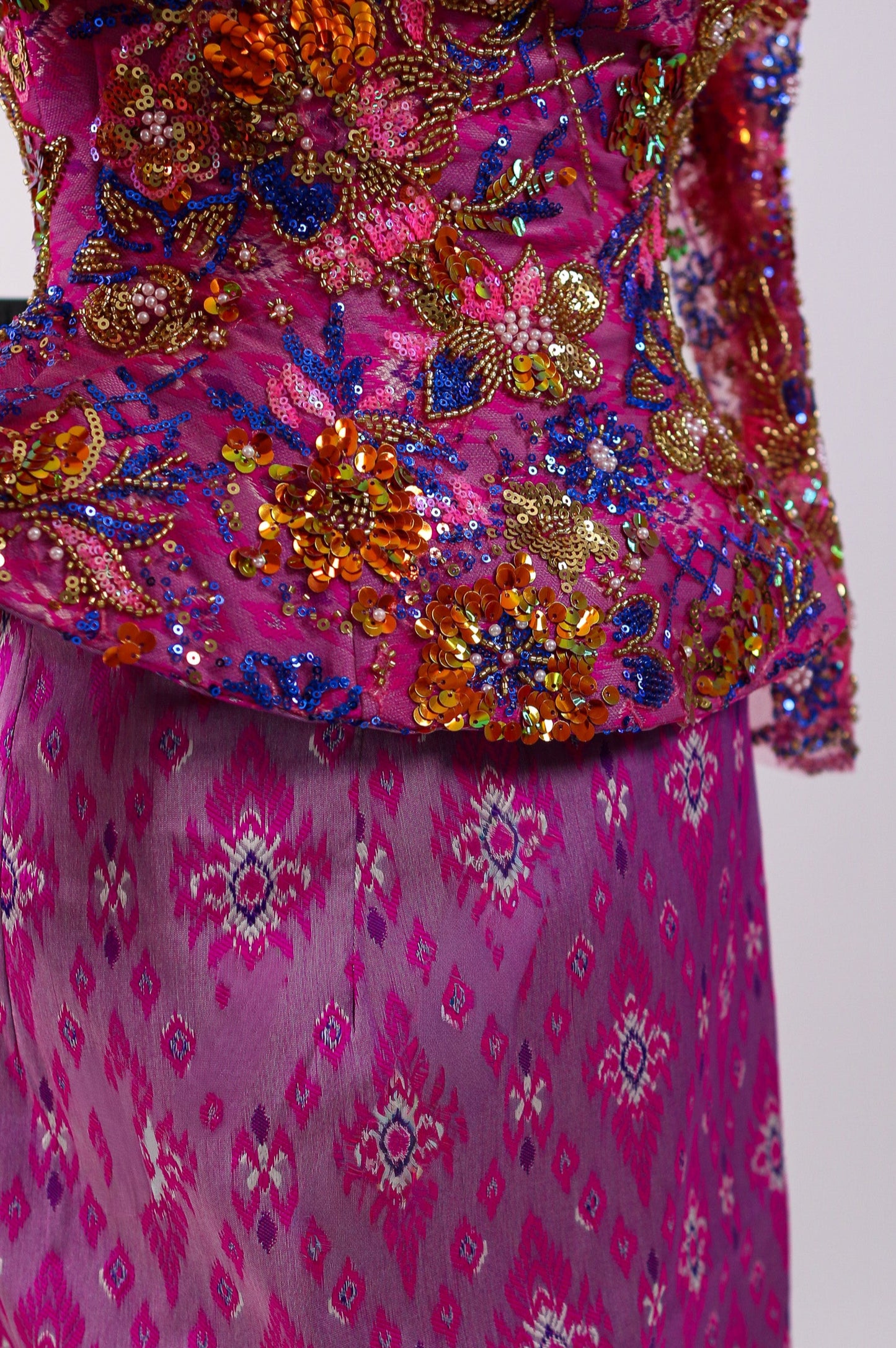 Traditional pink outfit with intricate patterns and embellishments on a white background