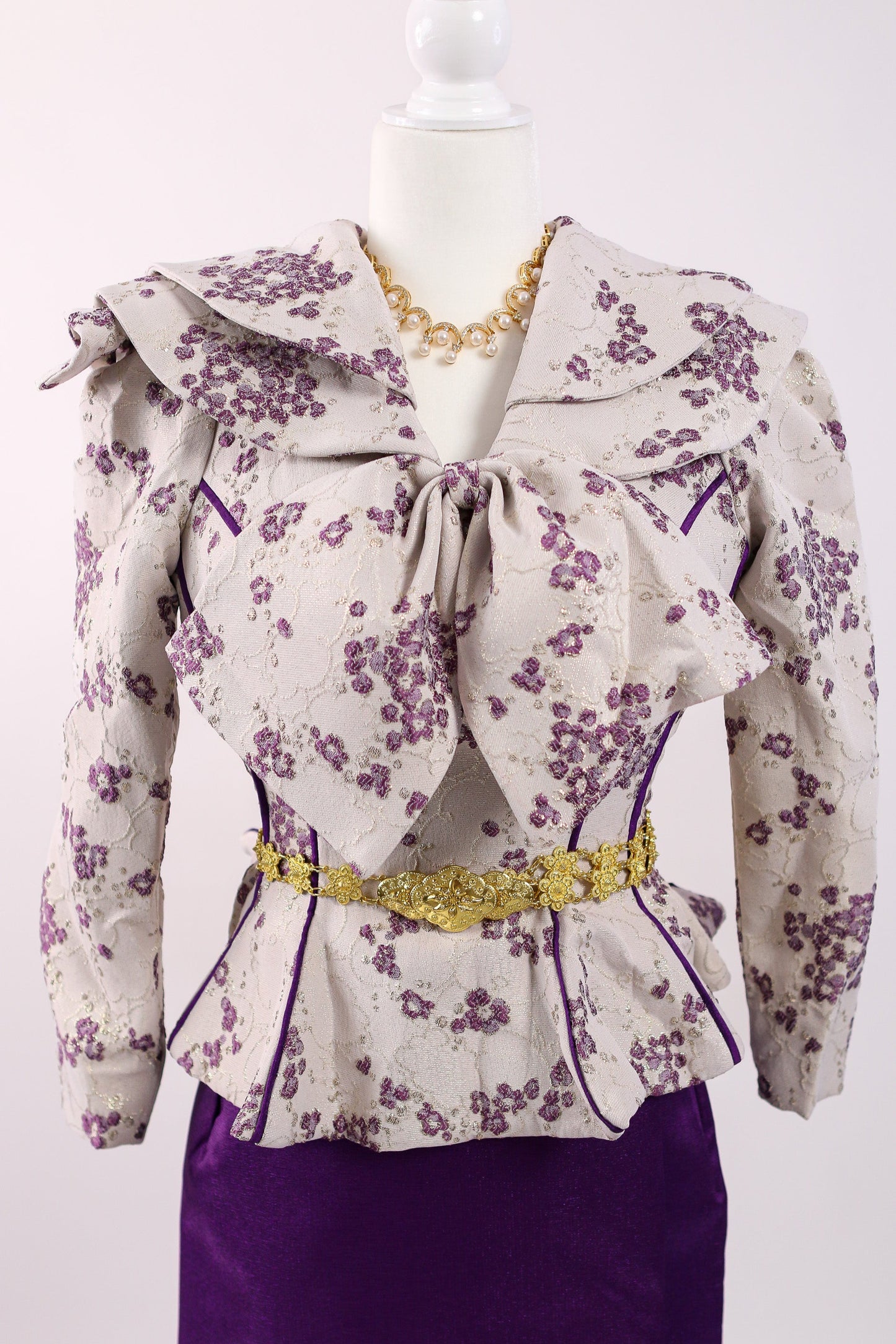 Floral blouse with a bow and purple skirt on a mannequin against a white background