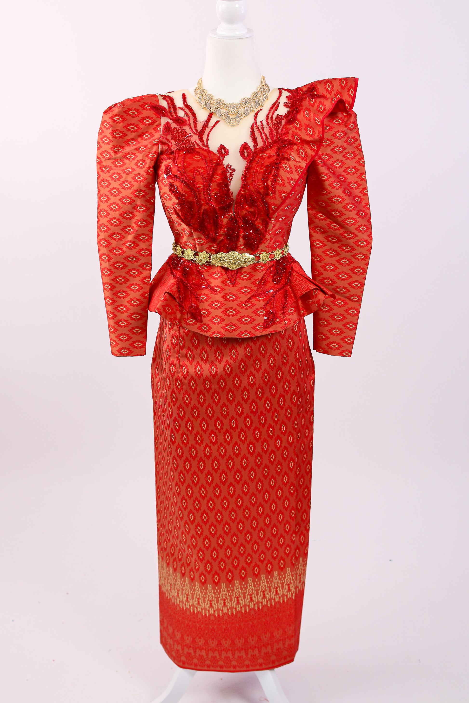 Red patterned dress with gold accents on a mannequin against a white background