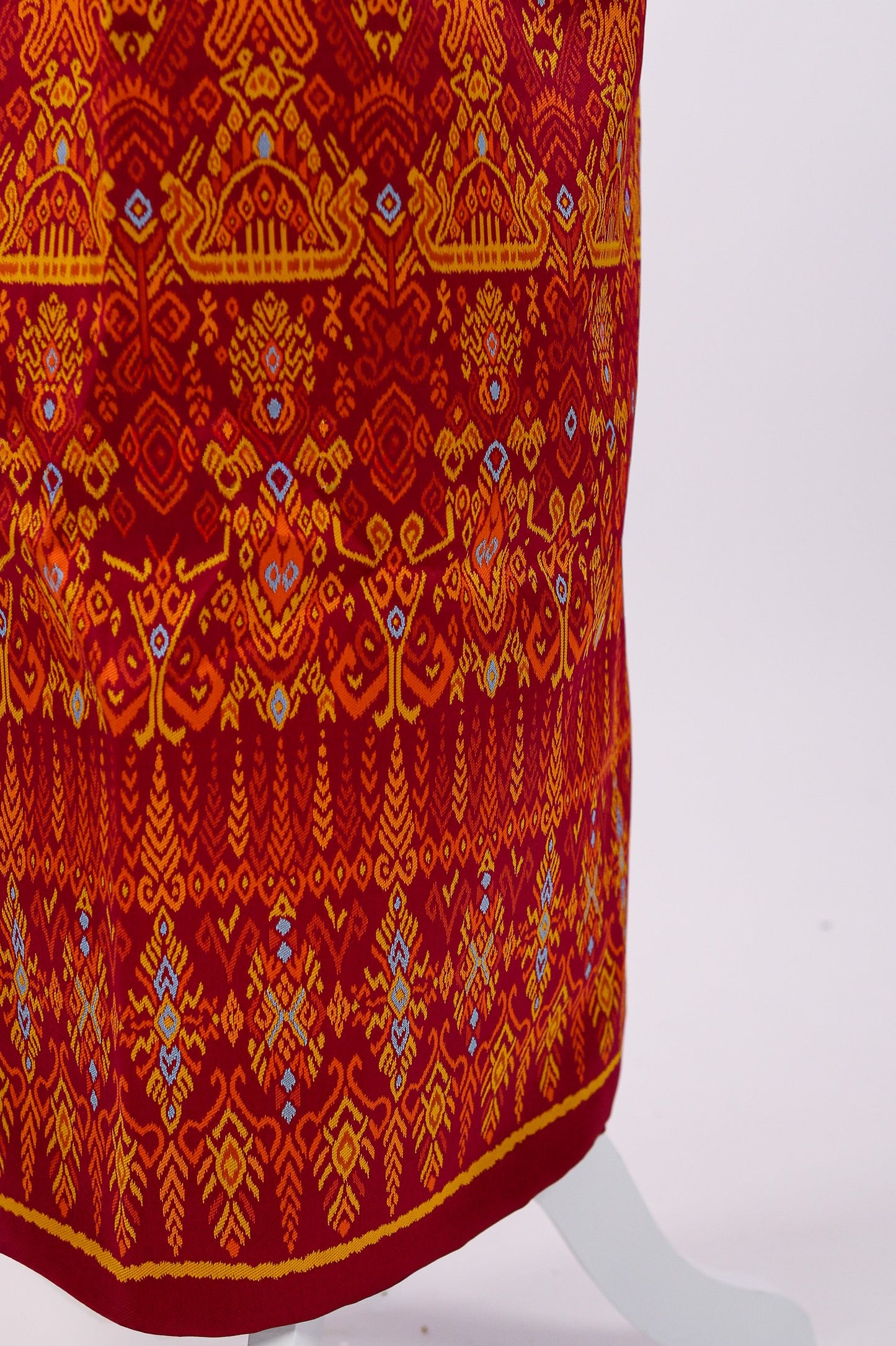Red fabric with intricate orange and blue patterns on a white background