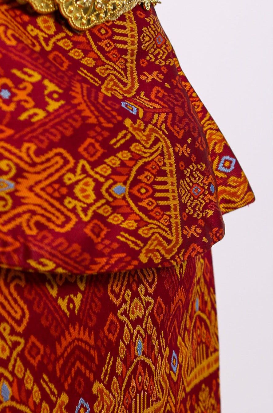 Traditional patterned outfit with a gold belt on a white background