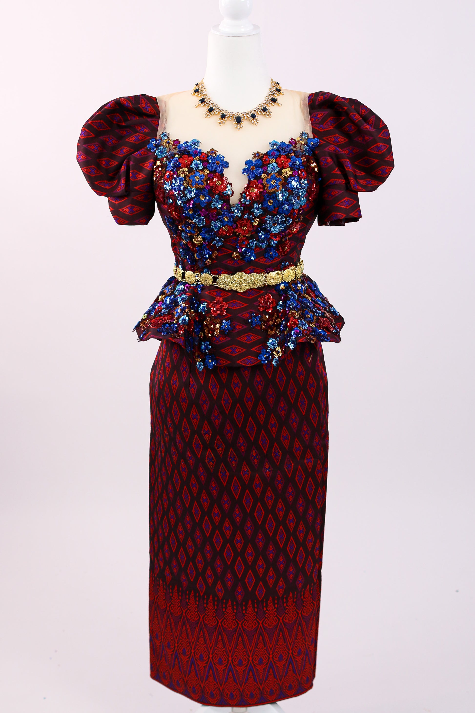 Red and blue patterned dress with floral embellishments on a white background