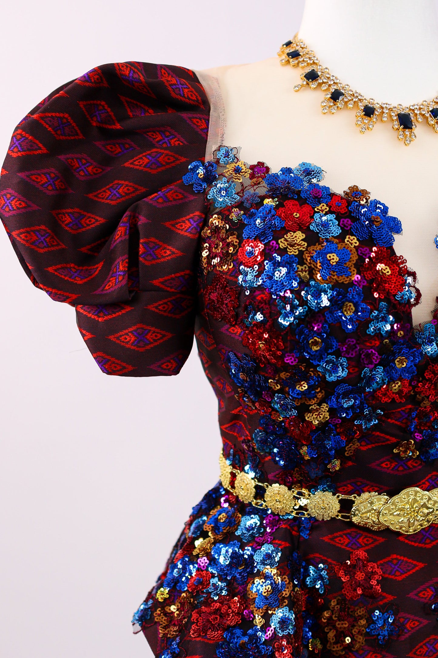 Colorful embroidered dress with floral patterns on a mannequin against a white background