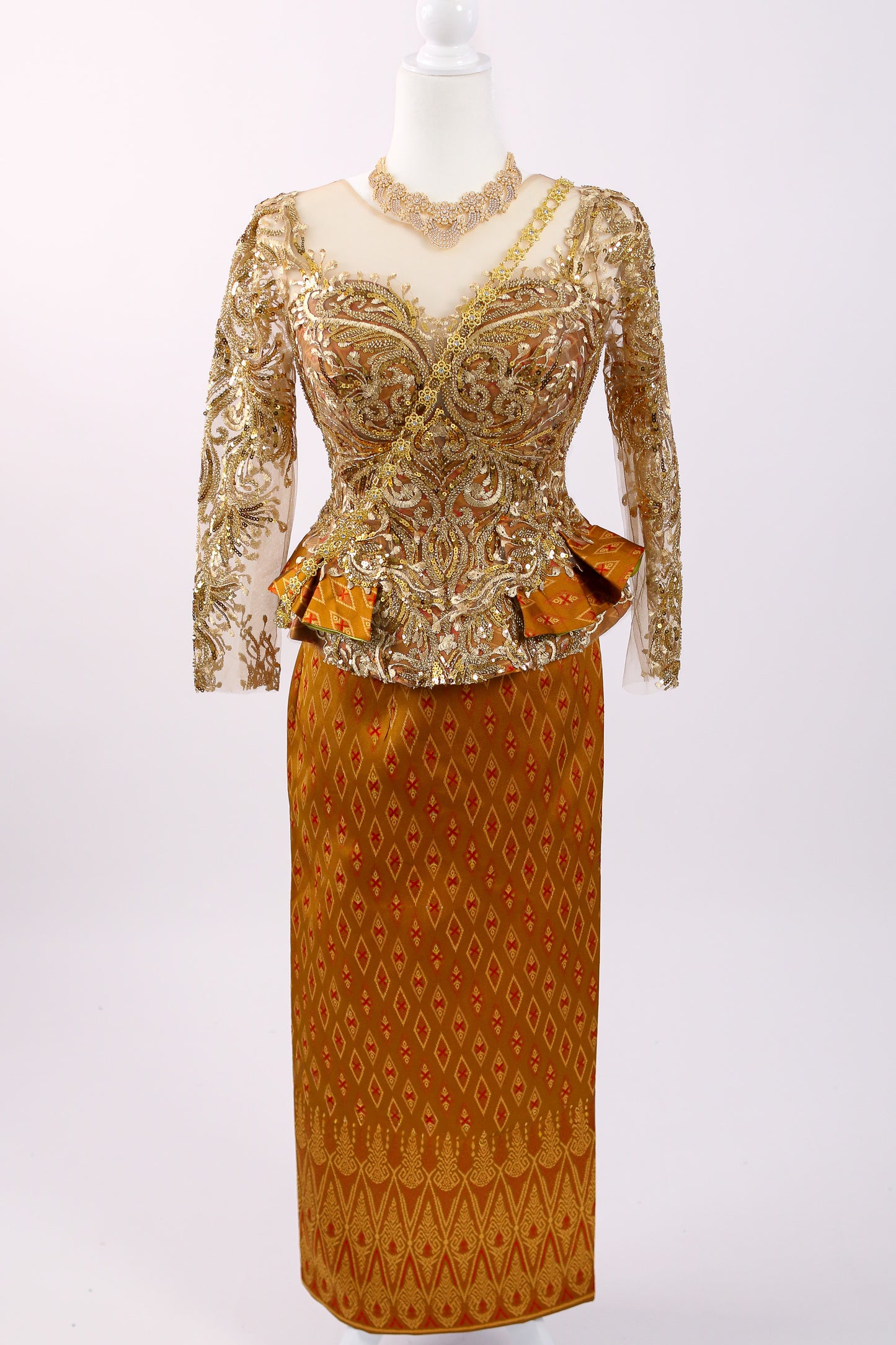 Gold and brown patterned dress on a mannequin against a white background