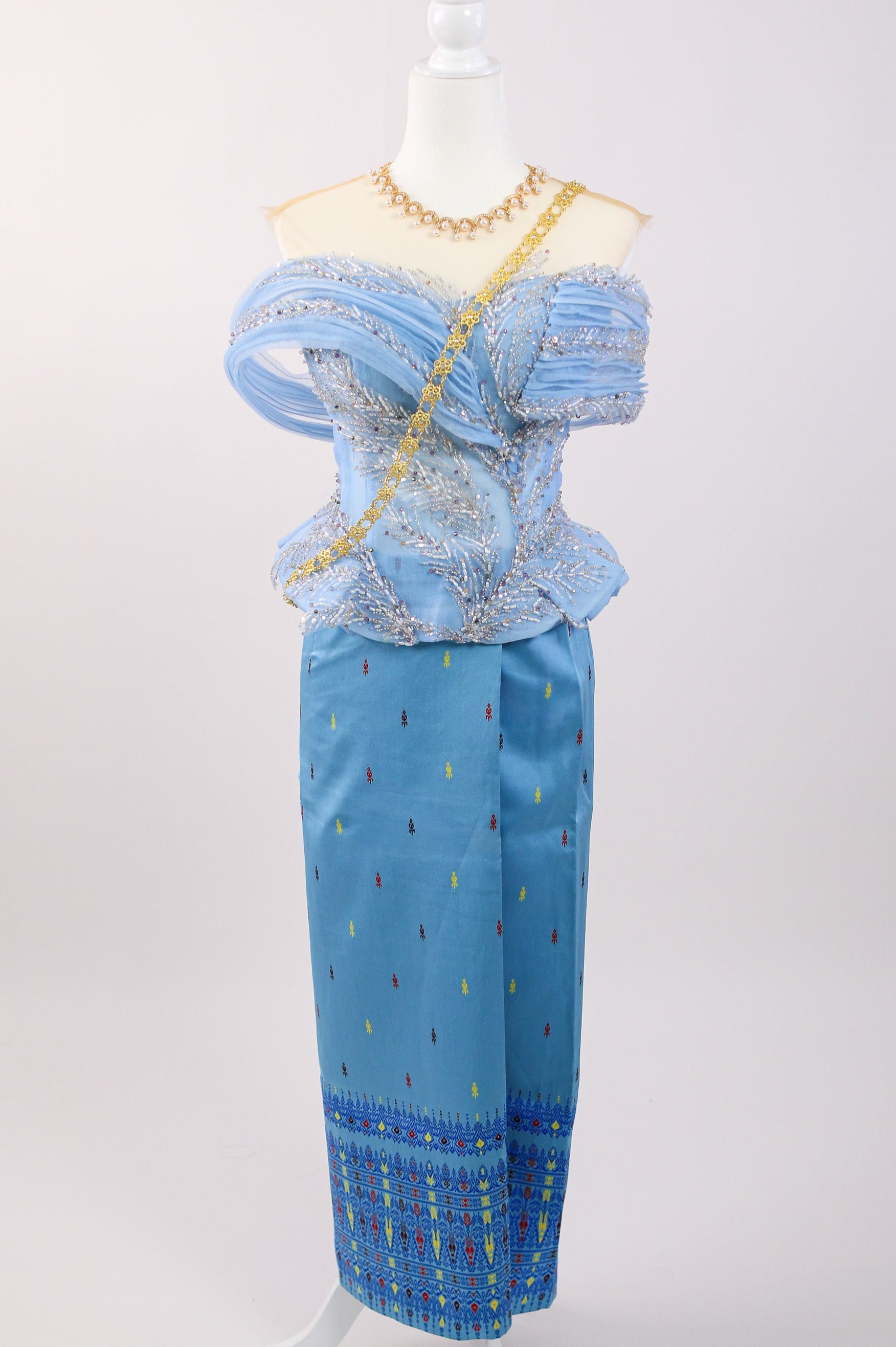 Mannequin wearing a blue outfit with intricate patterns on a white background