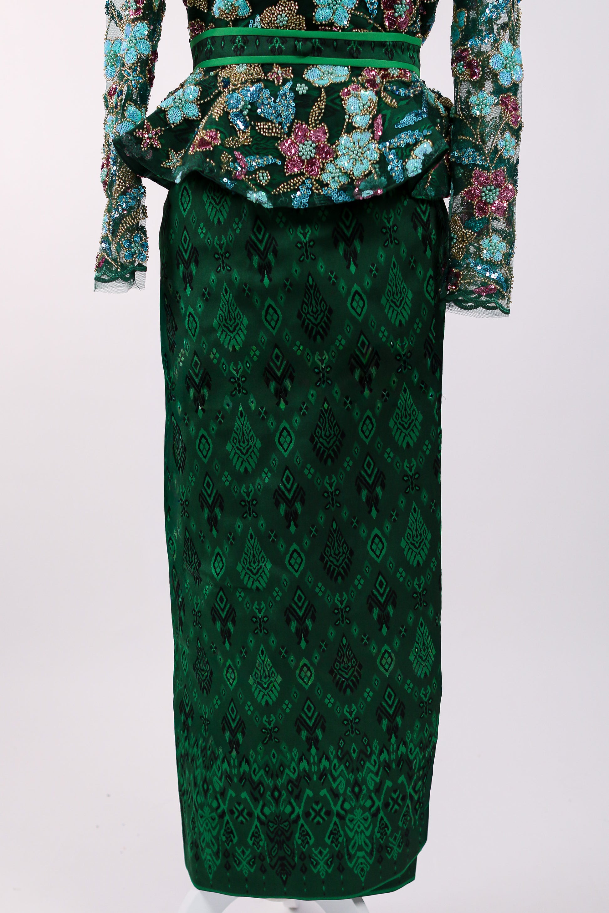 Green patterned dress with floral embellishments on a white background