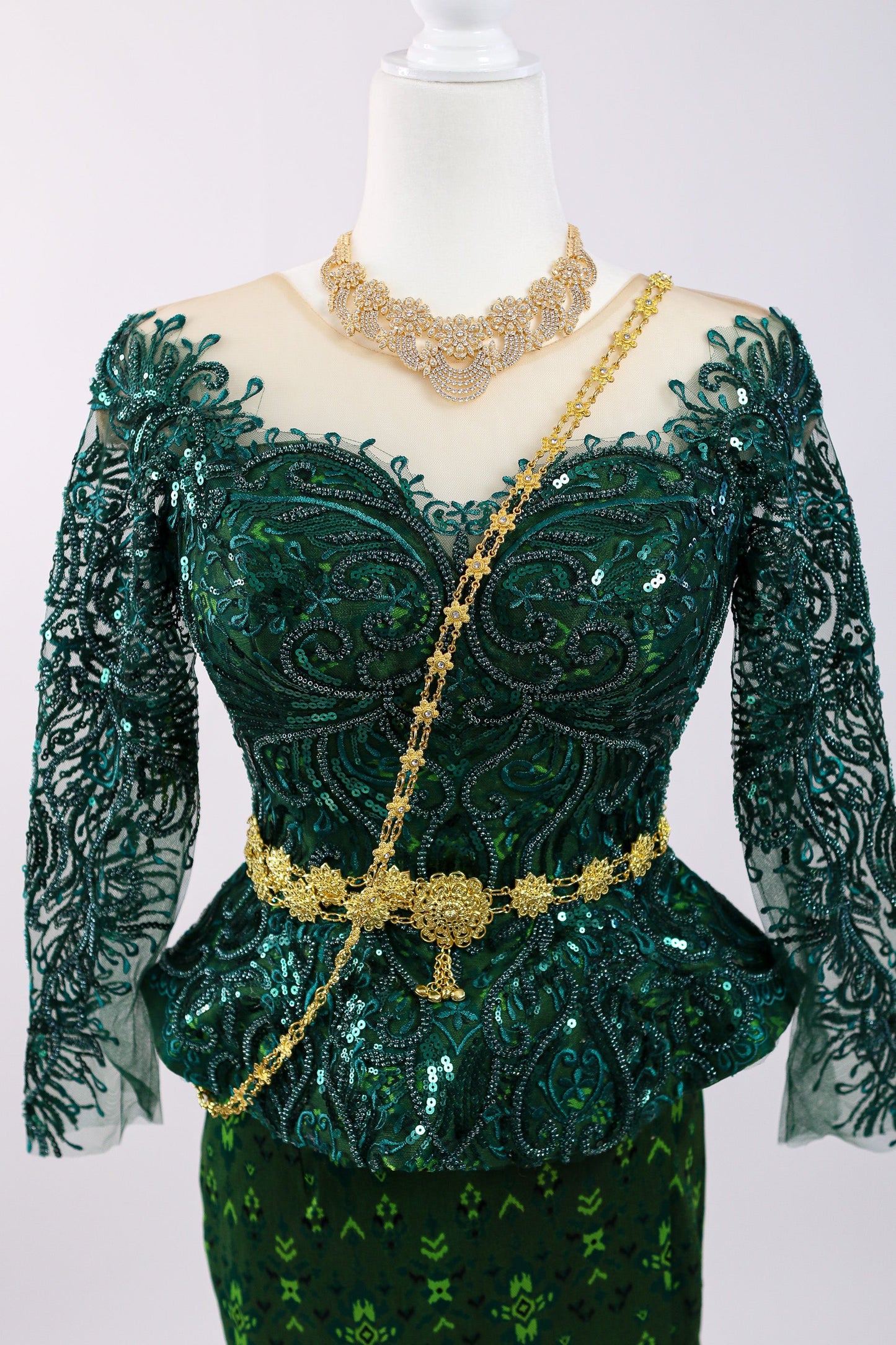 Green embroidered dress with gold accents on a mannequin against a white background
