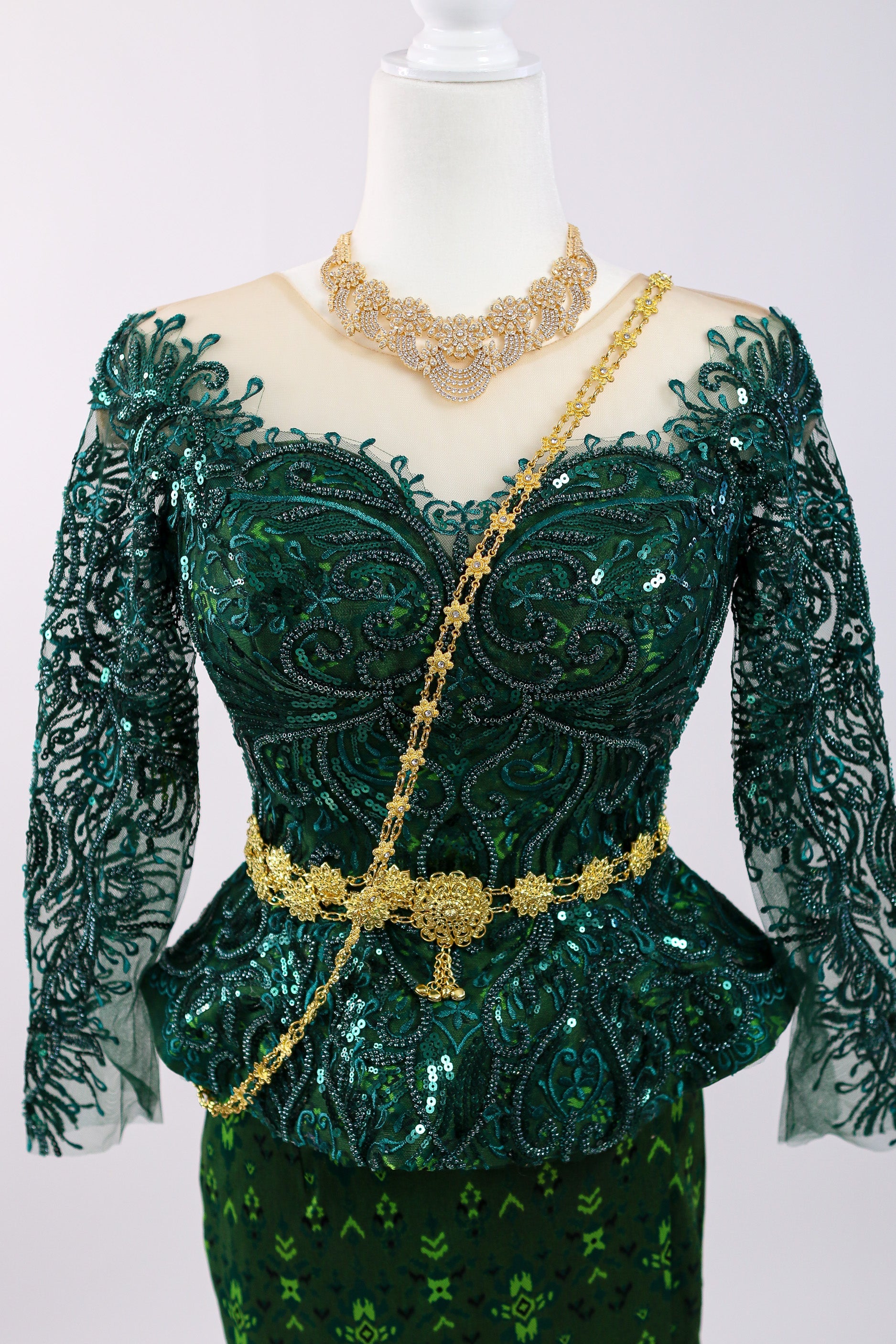 Green embroidered dress with gold accents on a mannequin against a white background