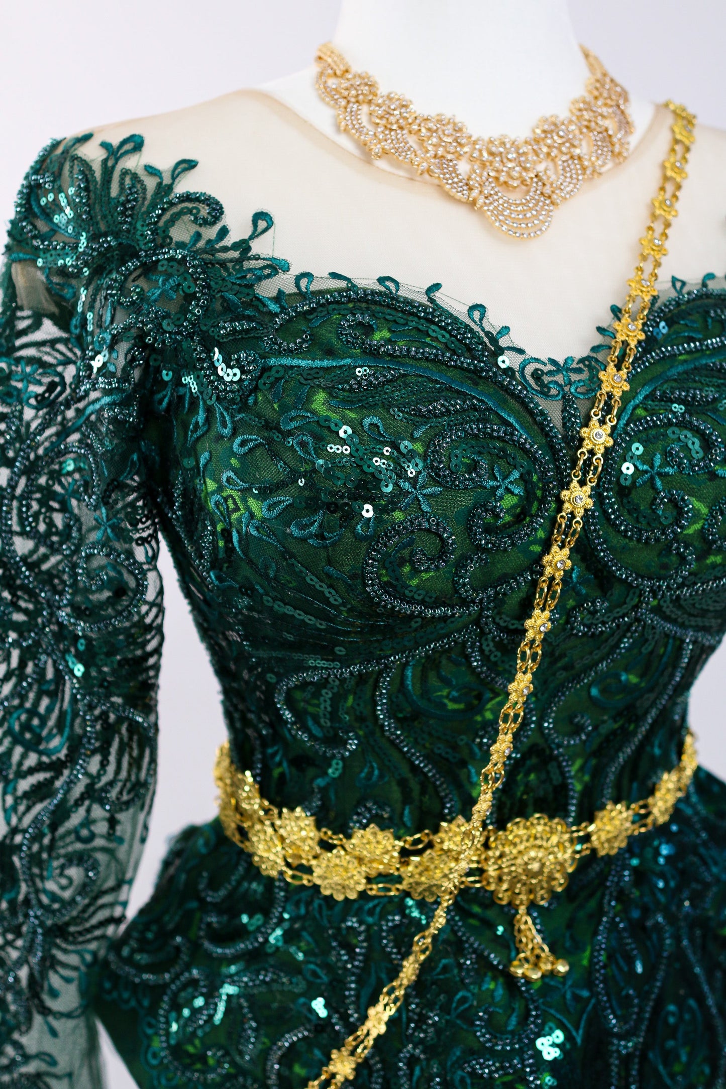 Green embroidered dress with gold accents on a mannequin against a white background