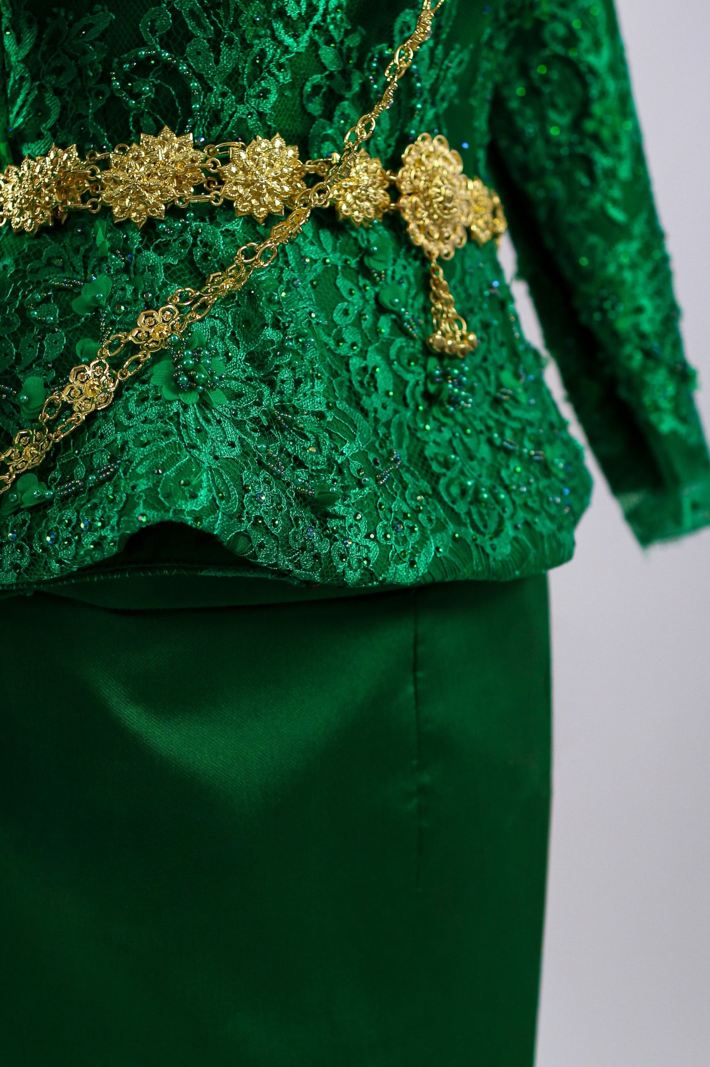 Green lace top with gold embellishments on a plain background