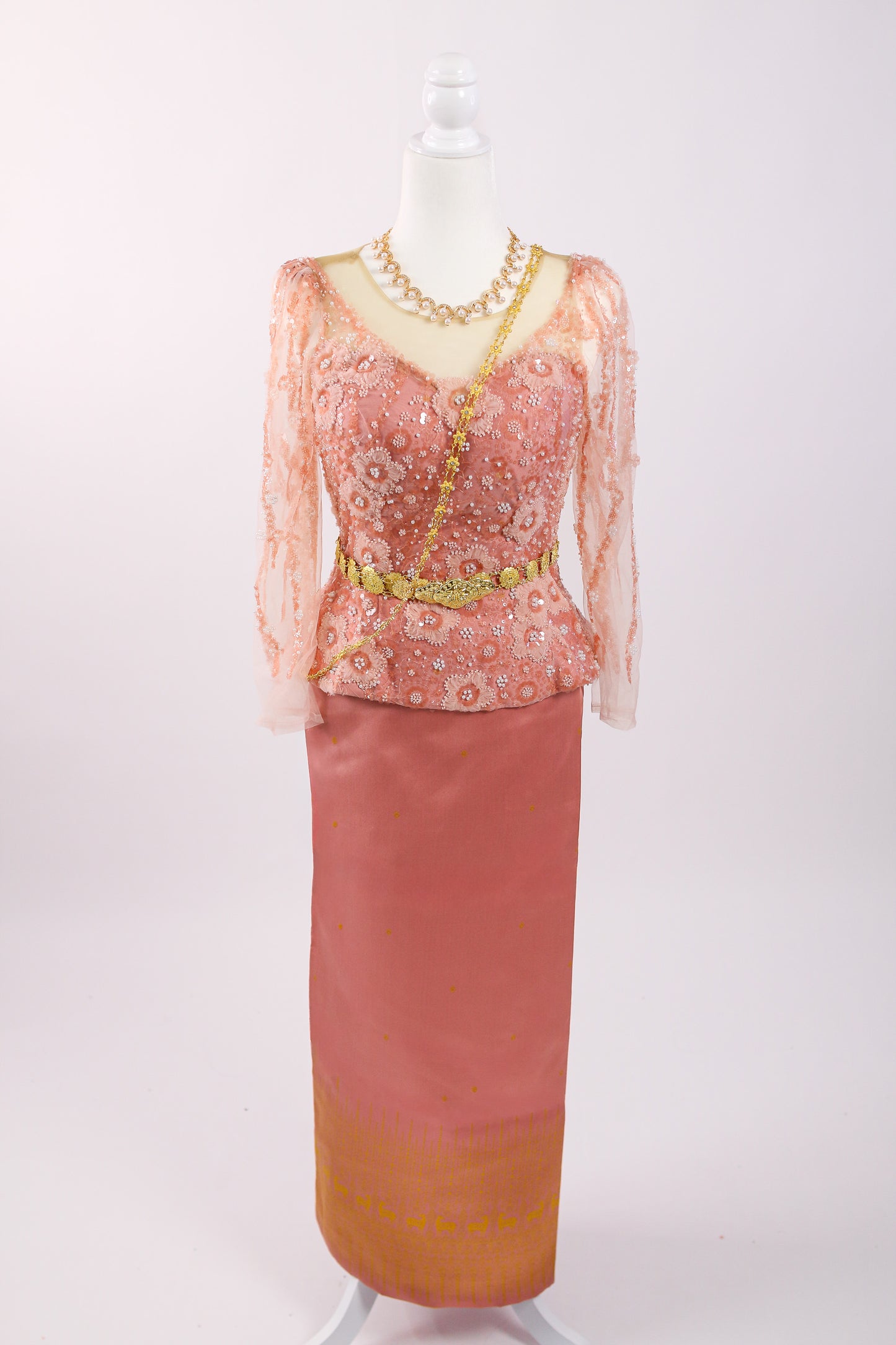 Traditional outfit with a pink top and skirt on a mannequin against a white background