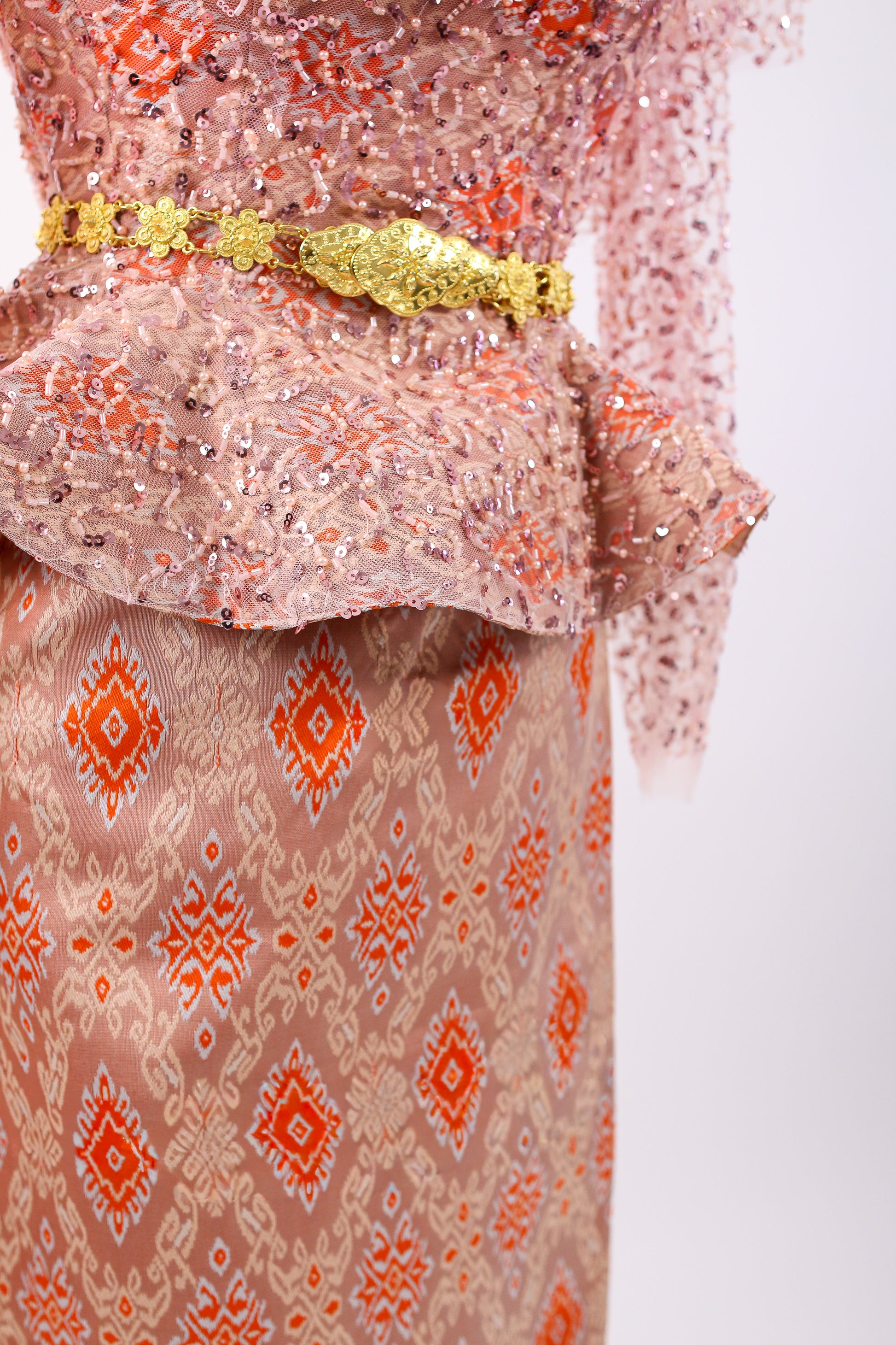 Traditional patterned garment with a gold belt on a white background