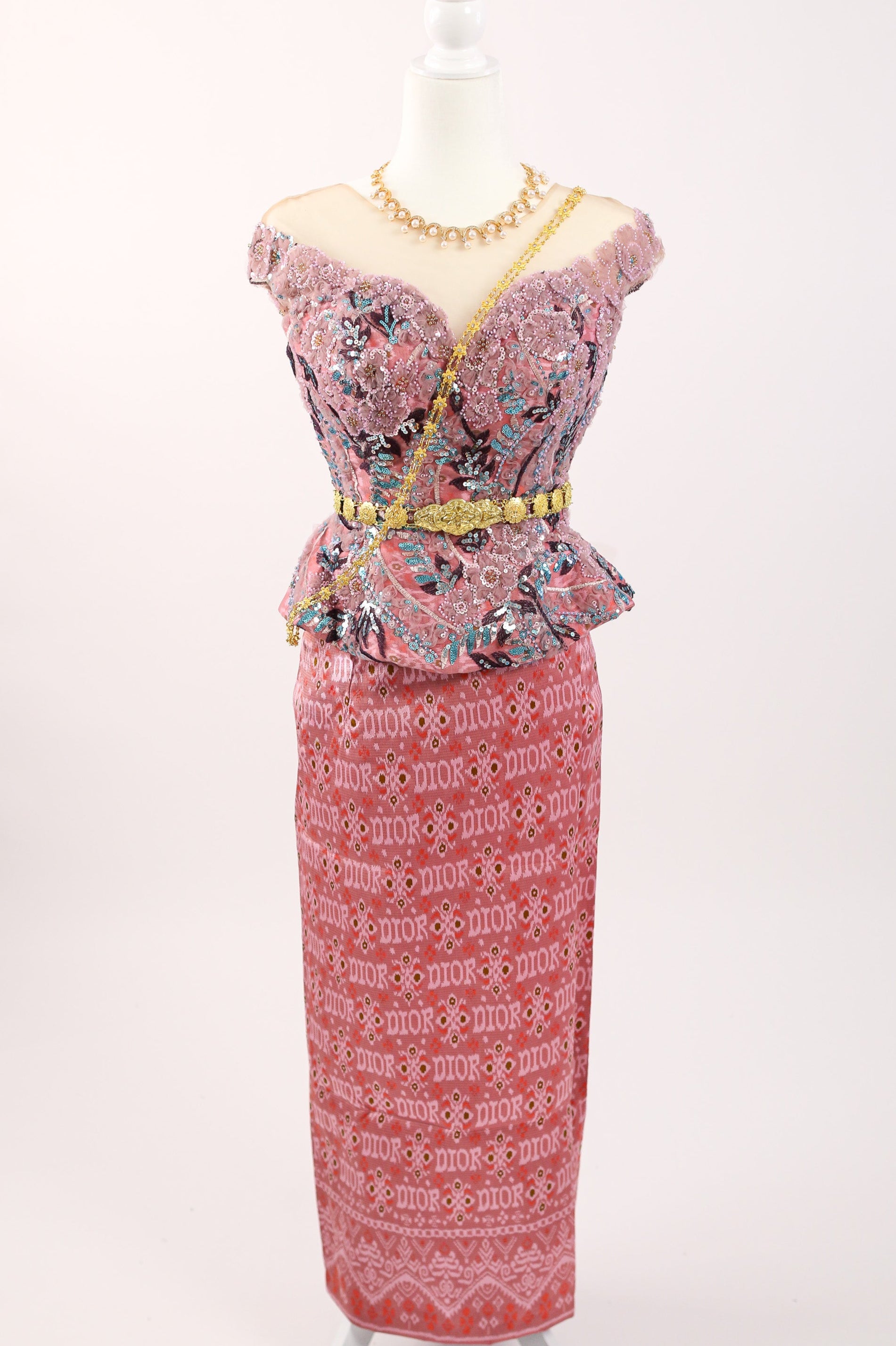Pink dress with floral patterns on a mannequin against a white background