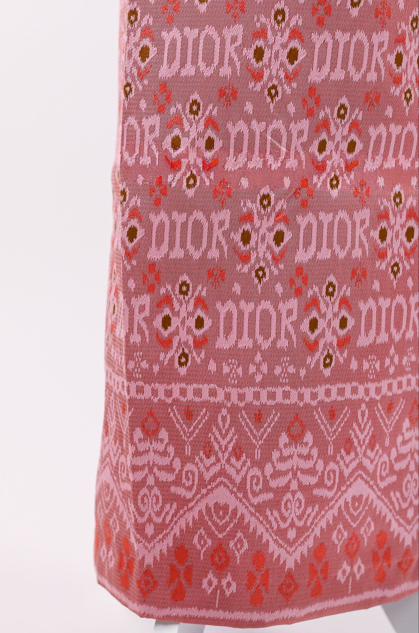 Pink fabric with Dior logo and floral pattern on a white background