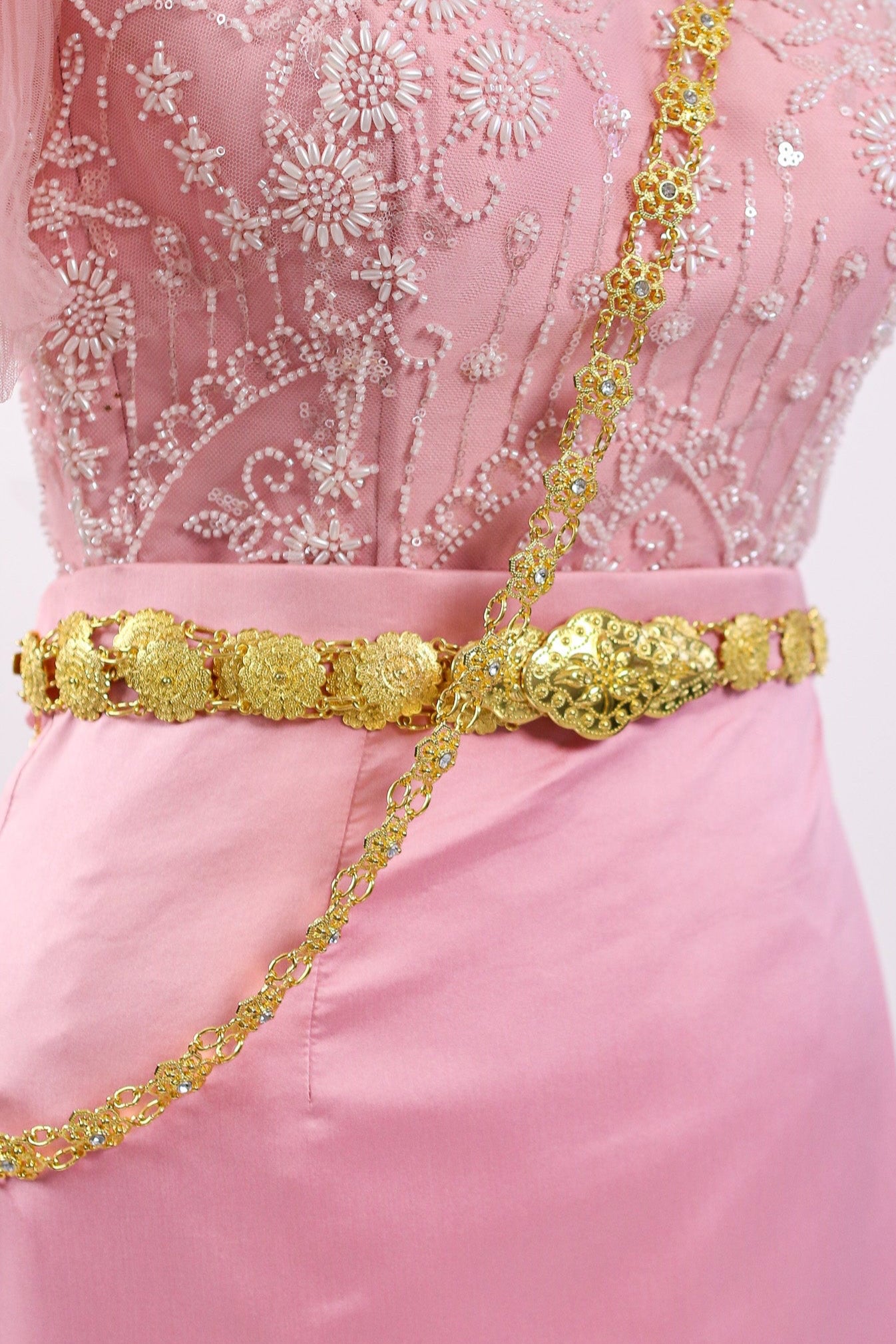 Pink dress with gold embellishments on a white background