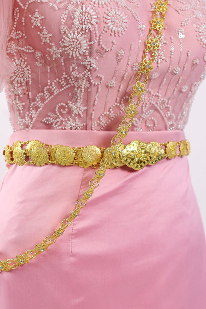 Pink dress with gold embellishments on a white background