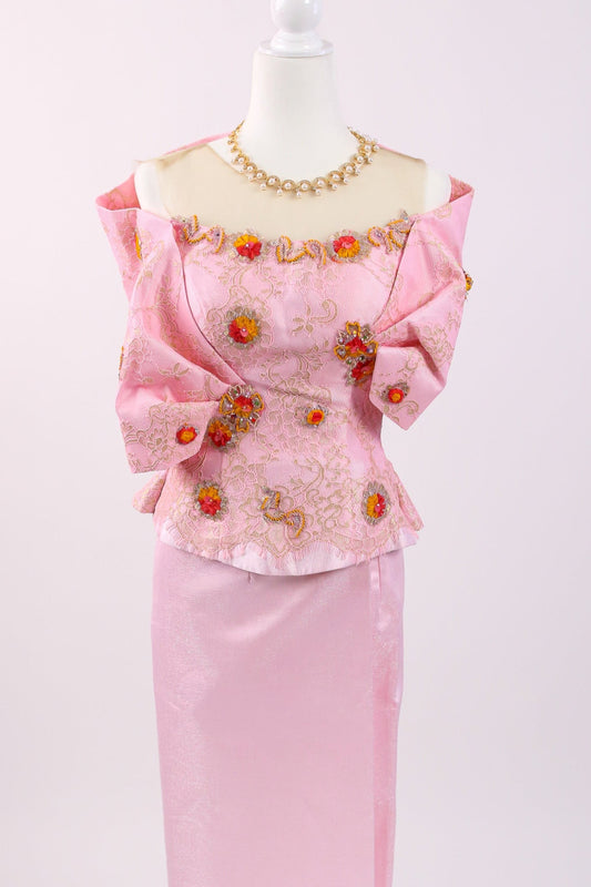 Pink traditional outfit with floral embroidery on a mannequin against a white background