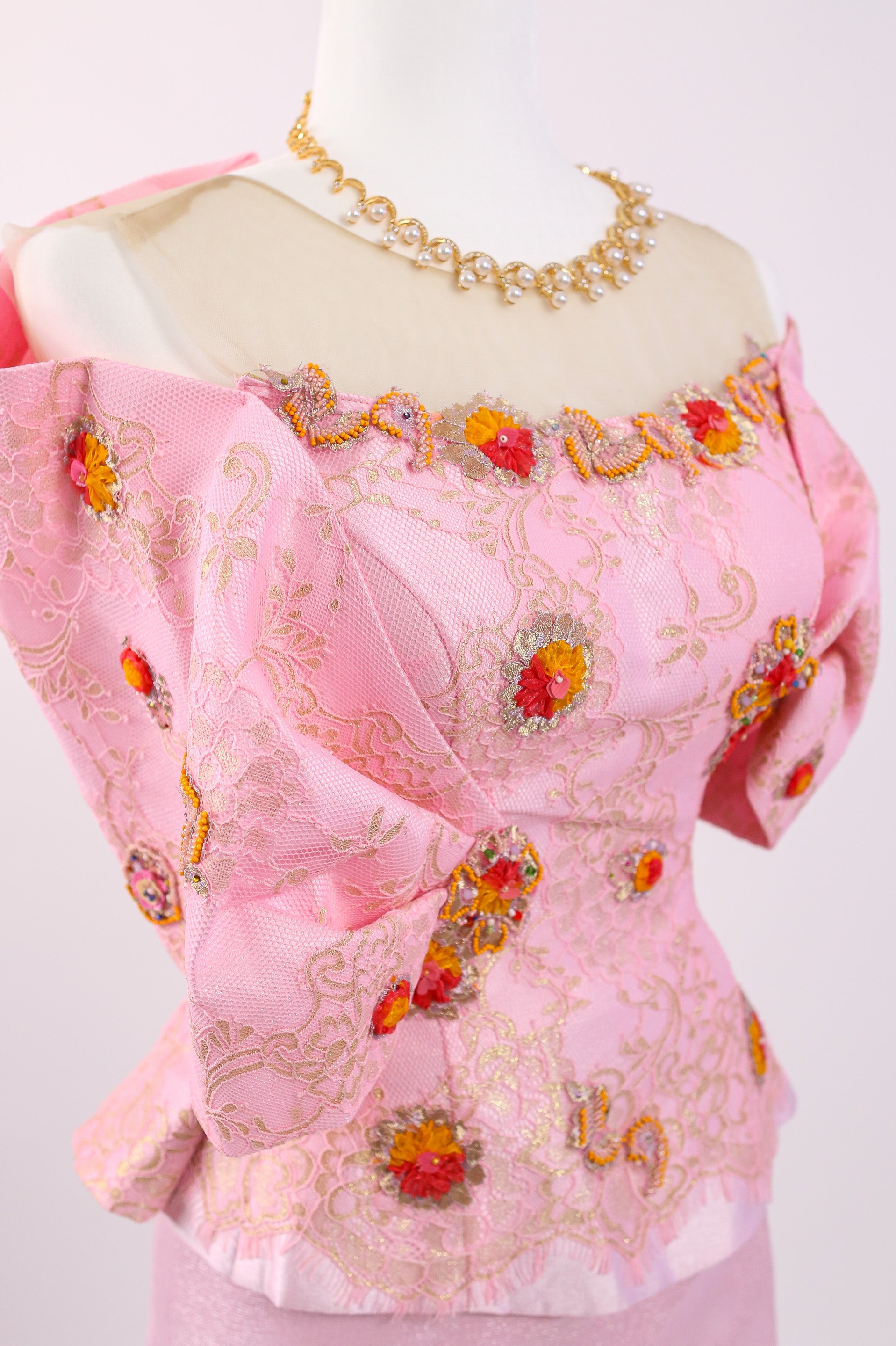 Pink embroidered blouse on a mannequin with a white background