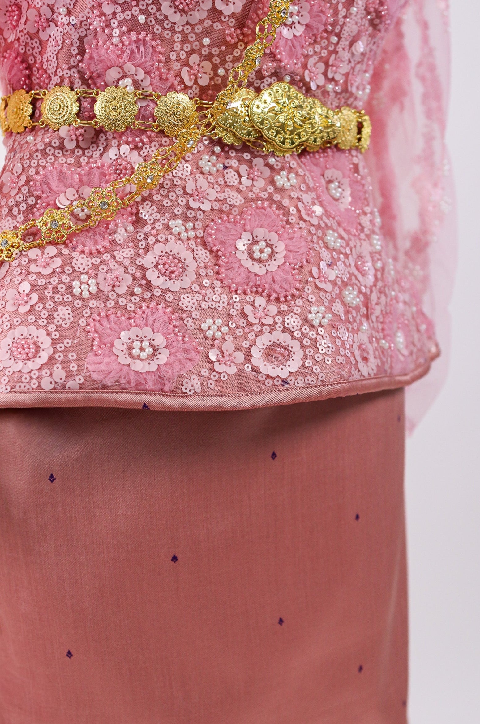 Pink embroidered top with gold detailing on a white background