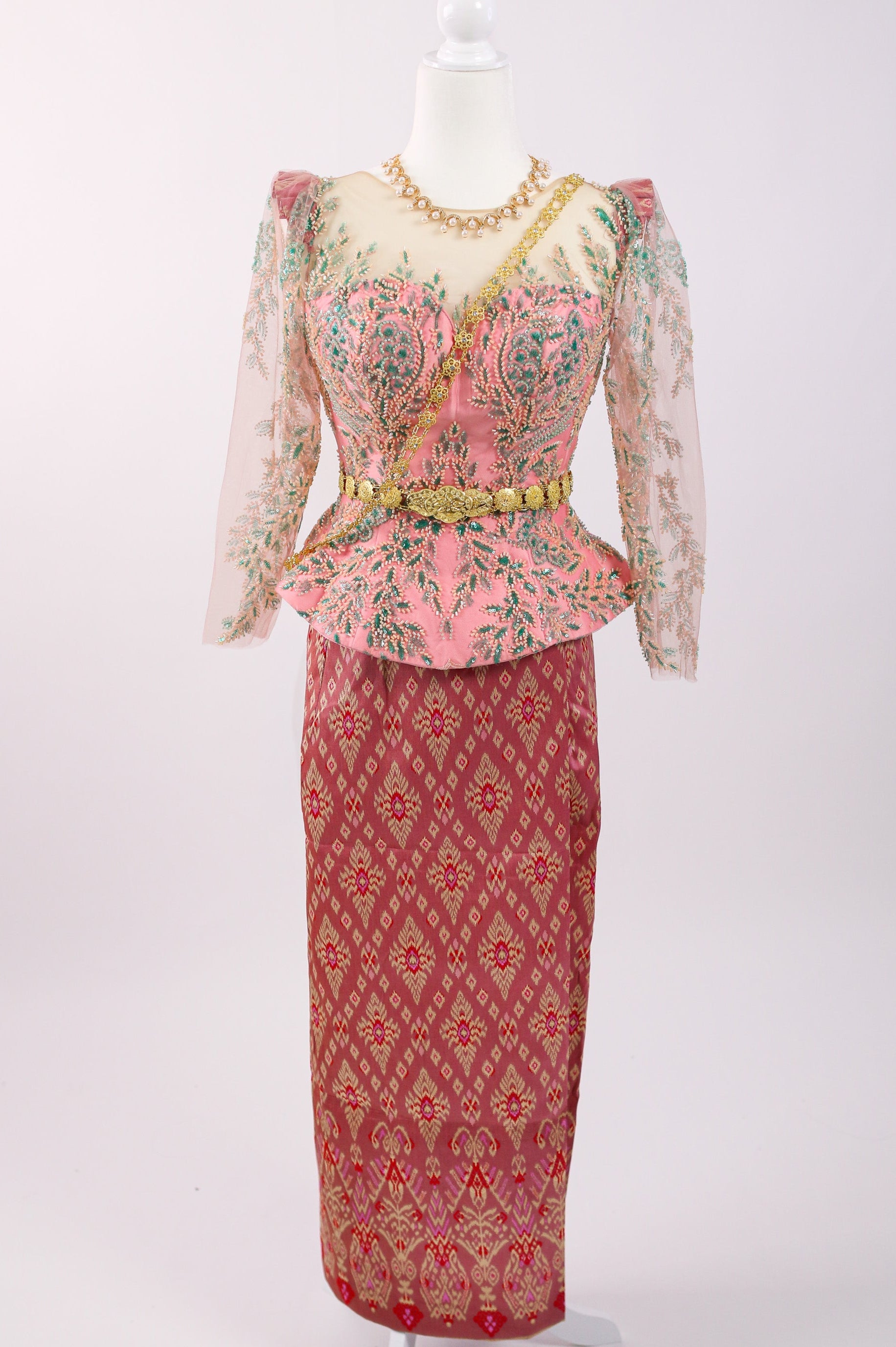 Traditional outfit with a pink patterned top and red skirt on a mannequin against a white background