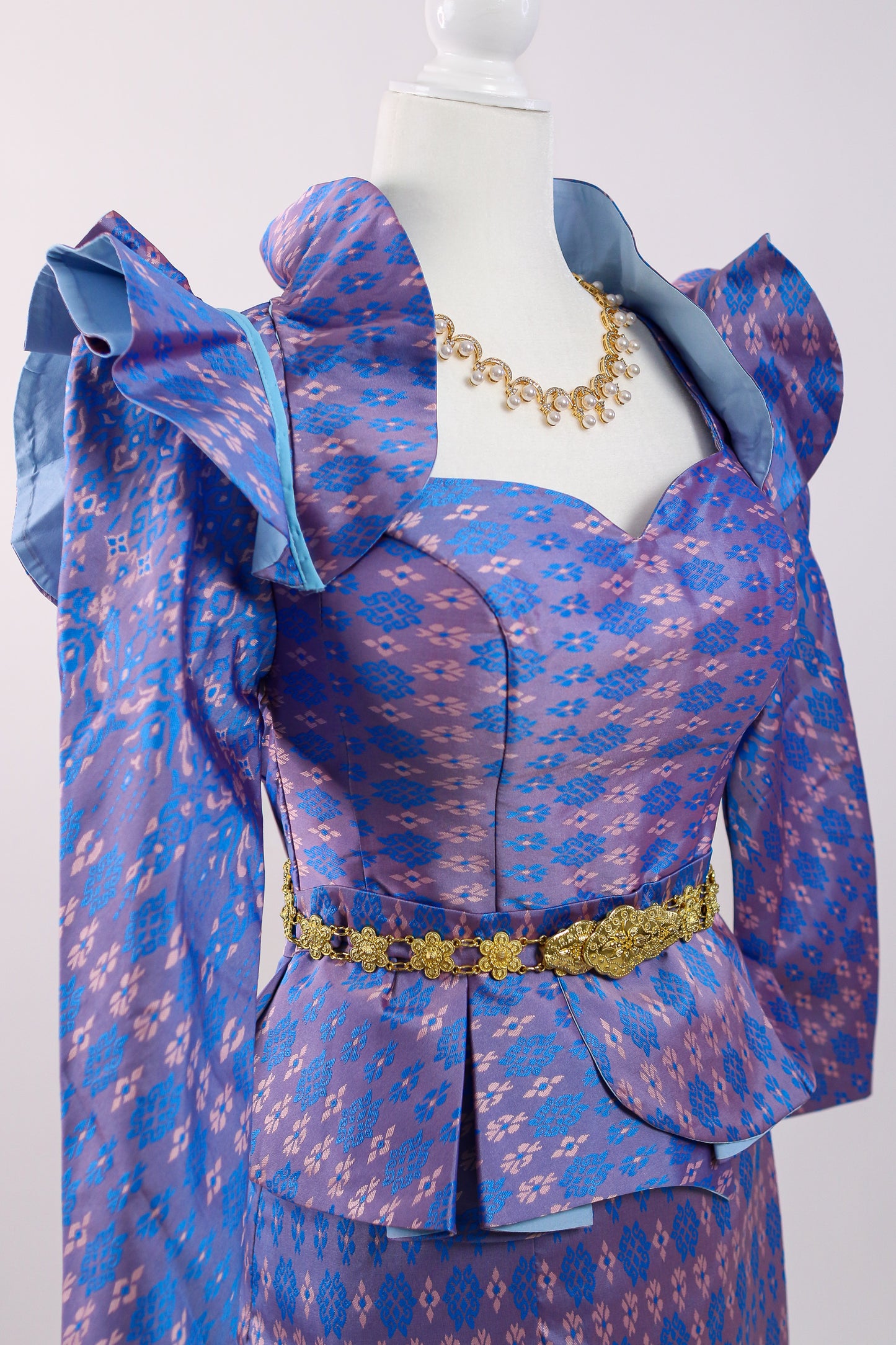 Blue patterned dress on a mannequin with gold jewelry against a white background