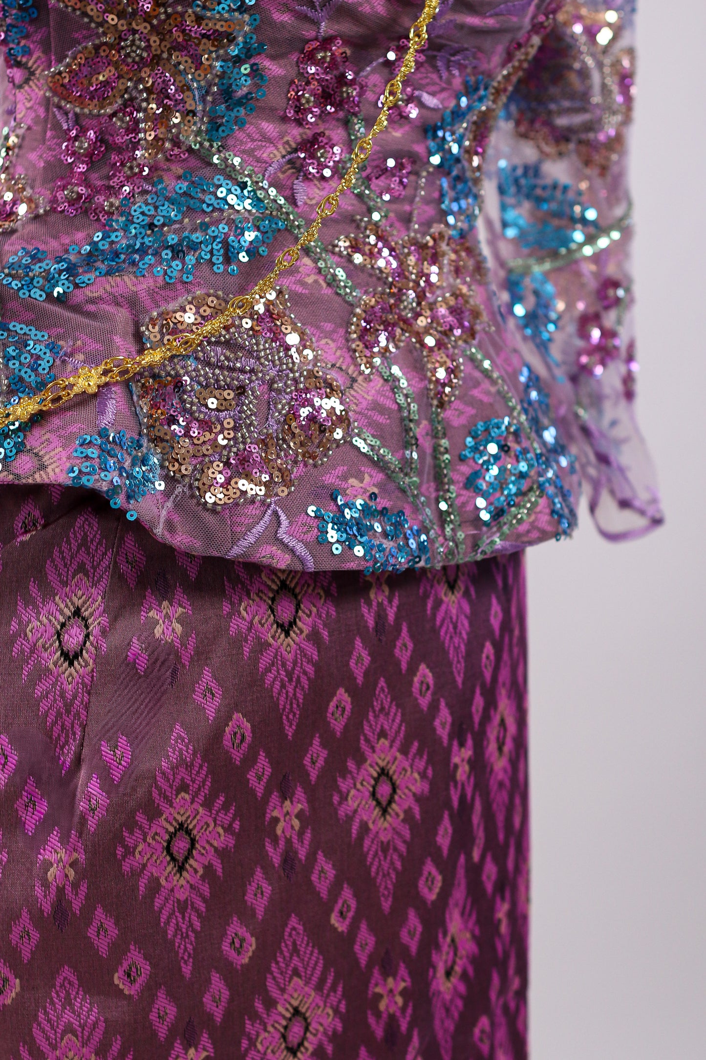 Decorative purple fabric with intricate patterns and sequins on a plain background