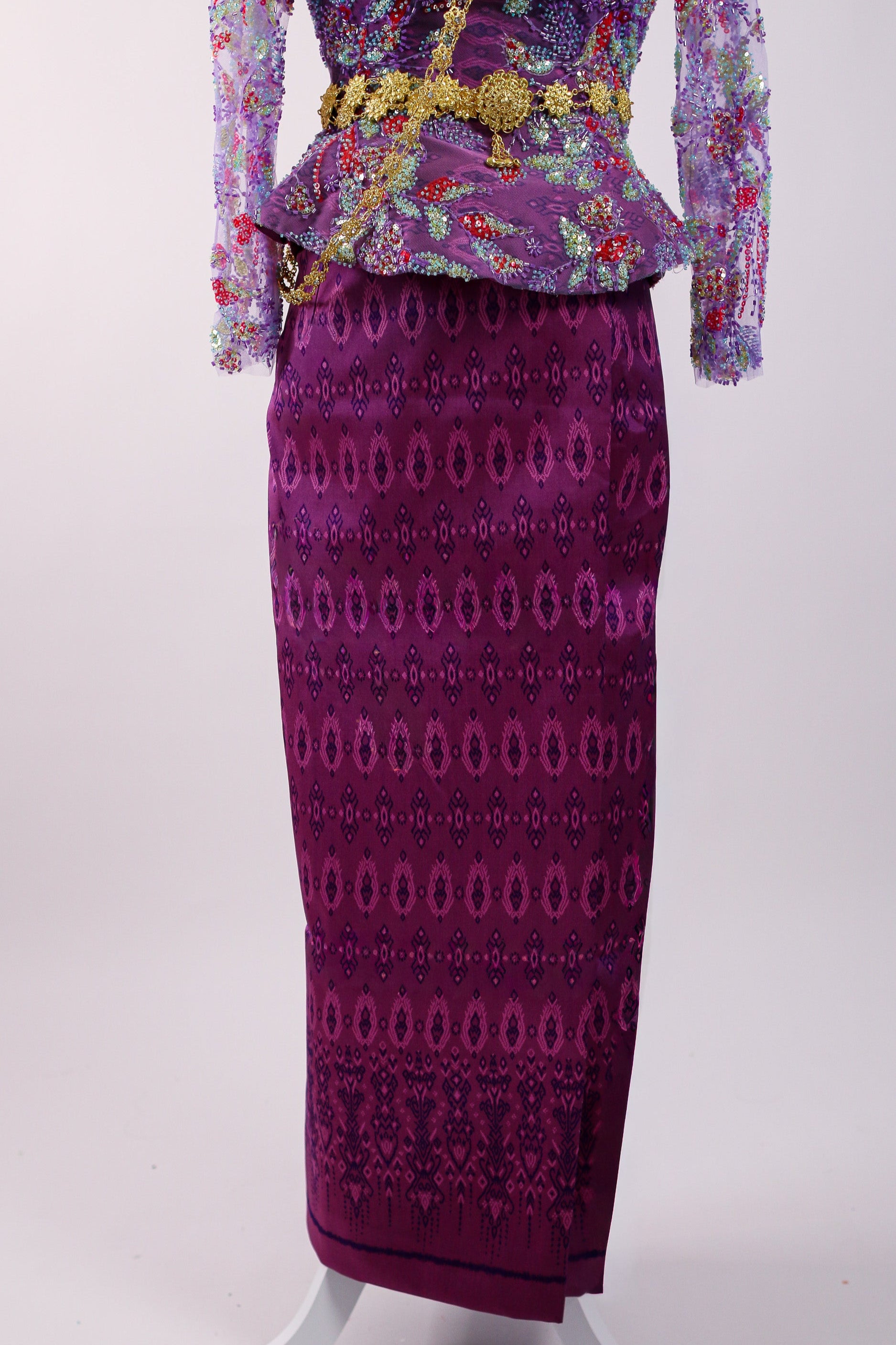 Traditional outfit with a purple embroidered top and matching skirt on a white background