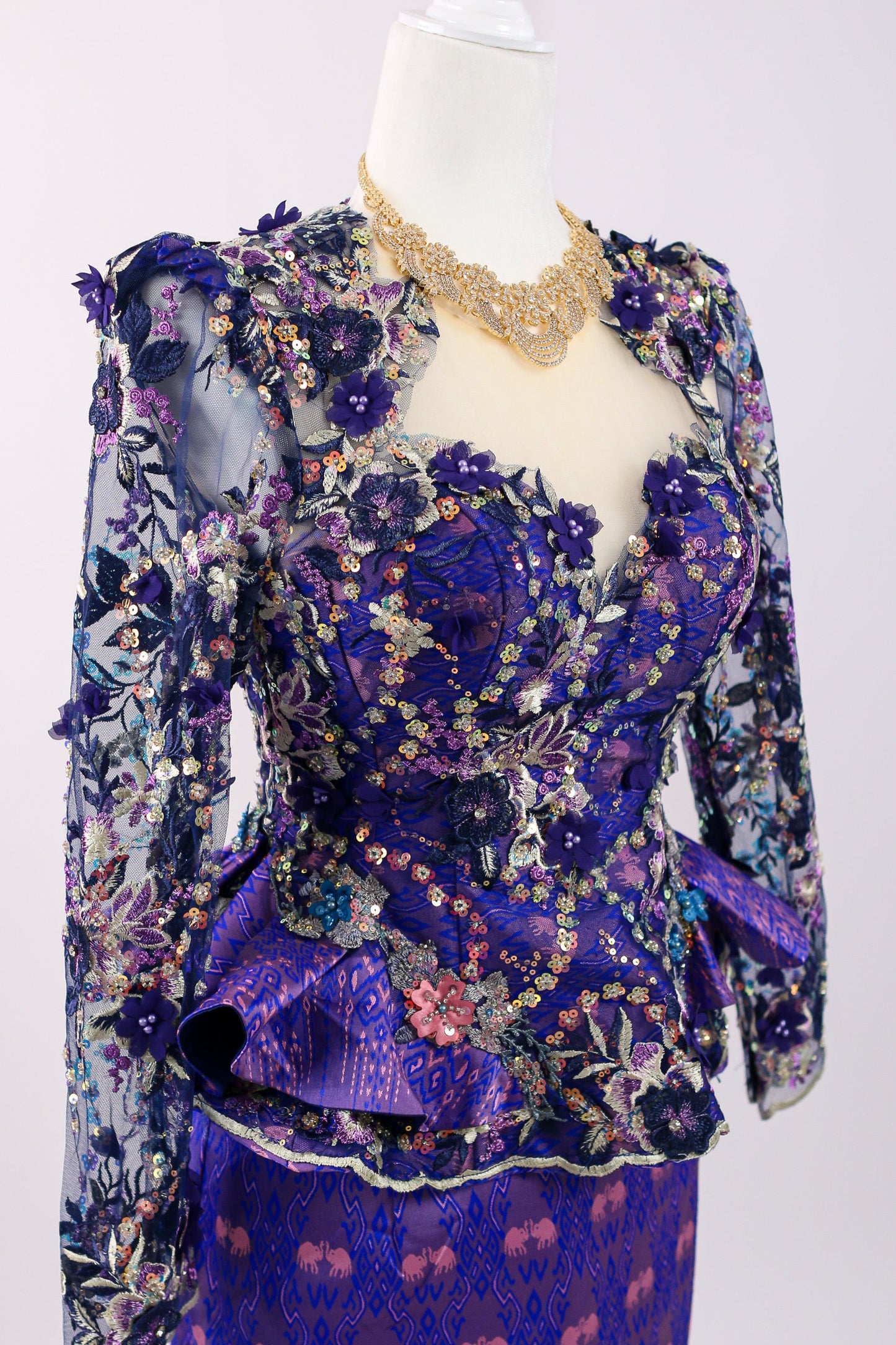 Mannequin wearing a floral and ruffled purple outfit on a white background