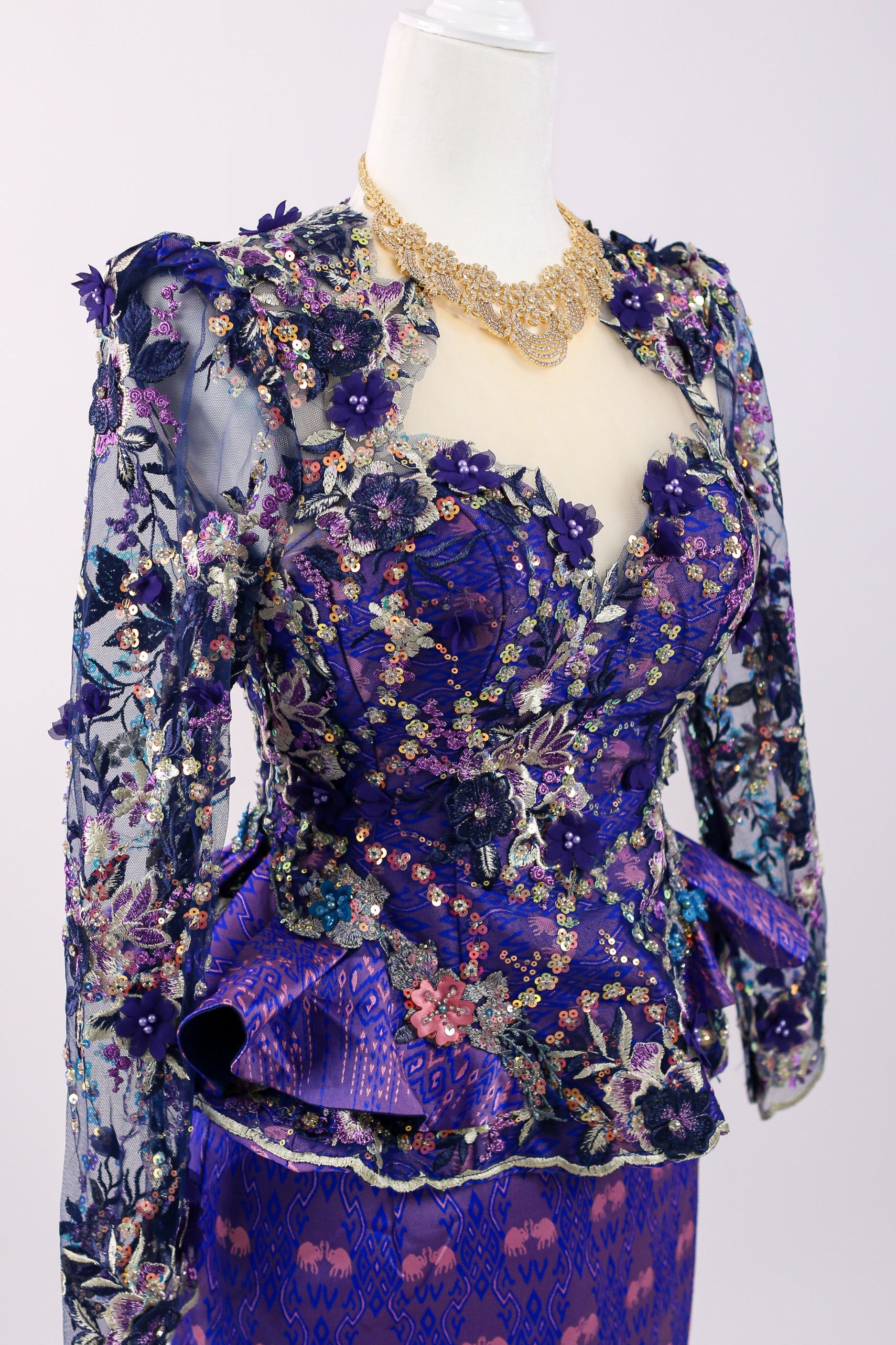 Mannequin wearing a floral and ruffled purple outfit on a white background