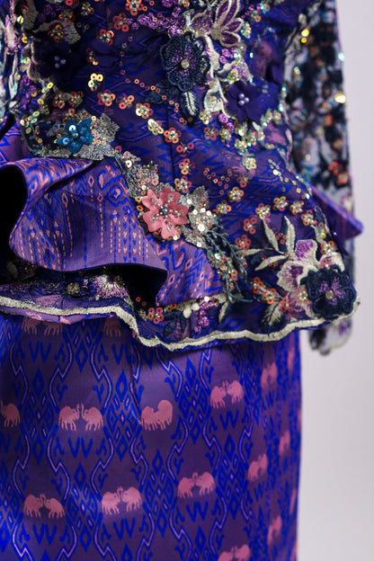 Close-up of a blue embroidered garment with intricate patterns on a plain background