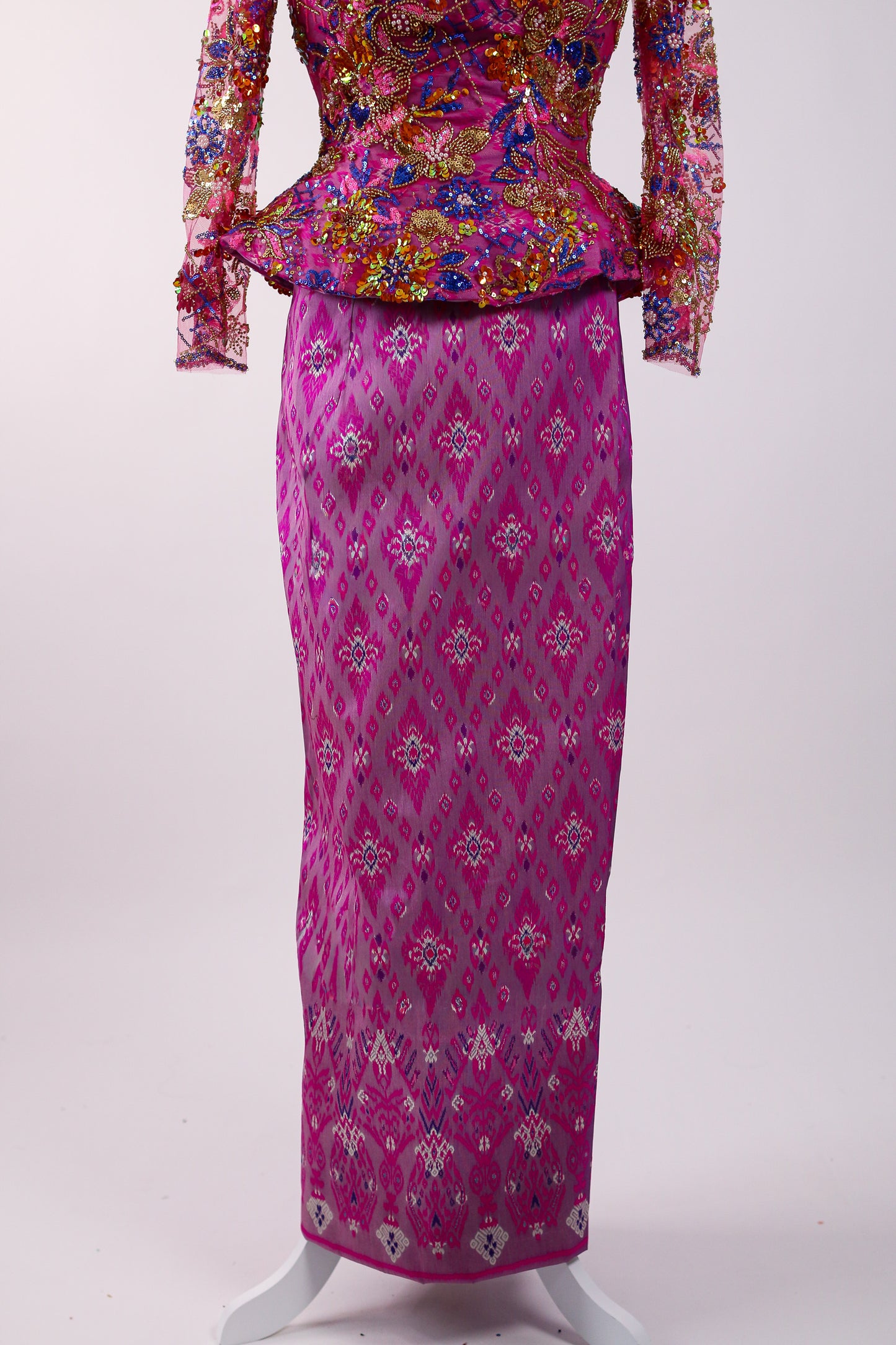Traditional outfit with floral top and pink patterned skirt on a white background