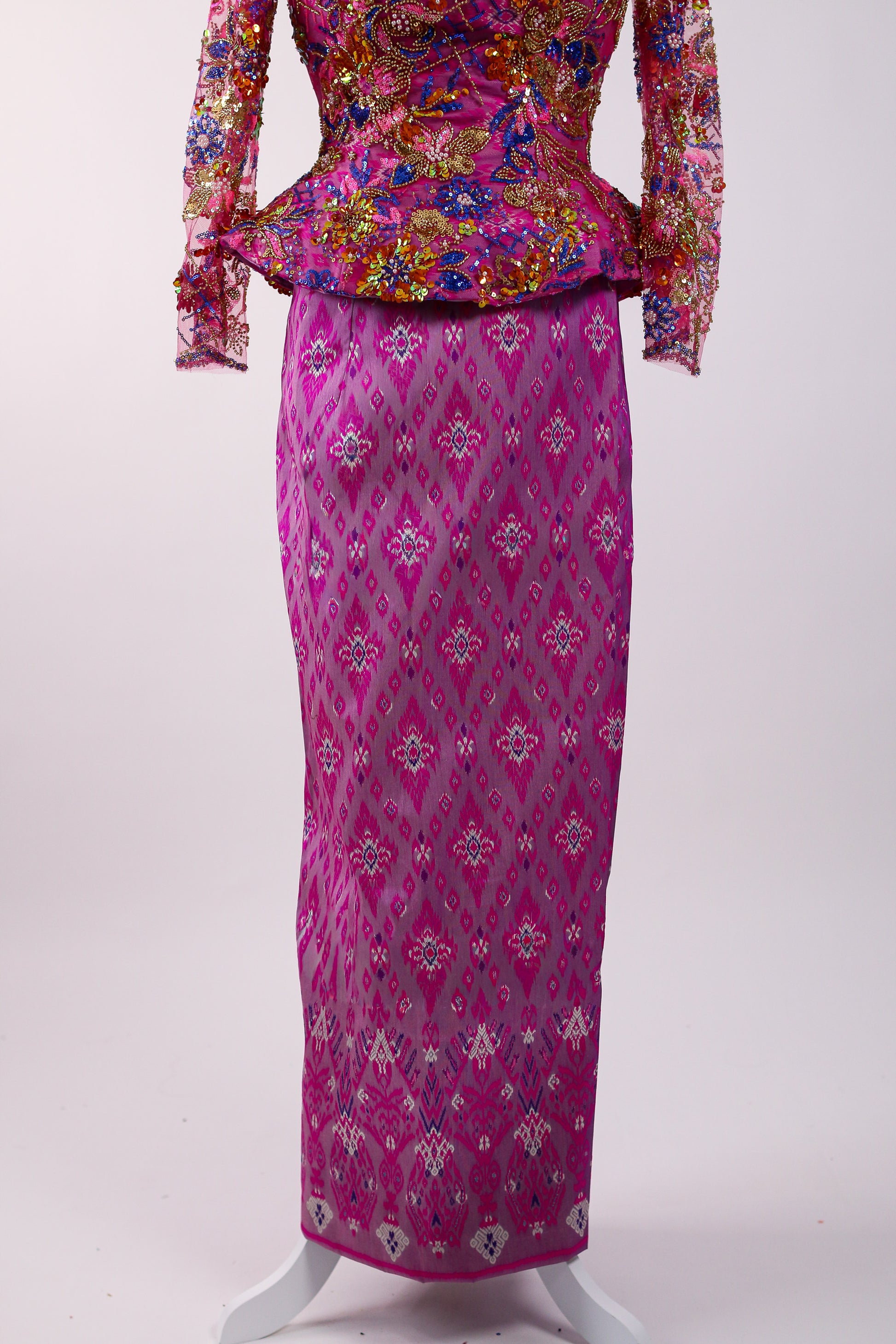Traditional outfit with floral top and pink patterned skirt on a white background