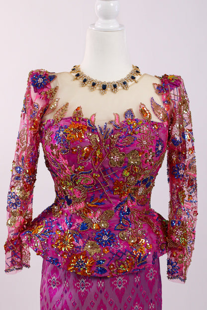 Mannequin wearing a vibrant pink and multicolored dress with intricate patterns on a white background