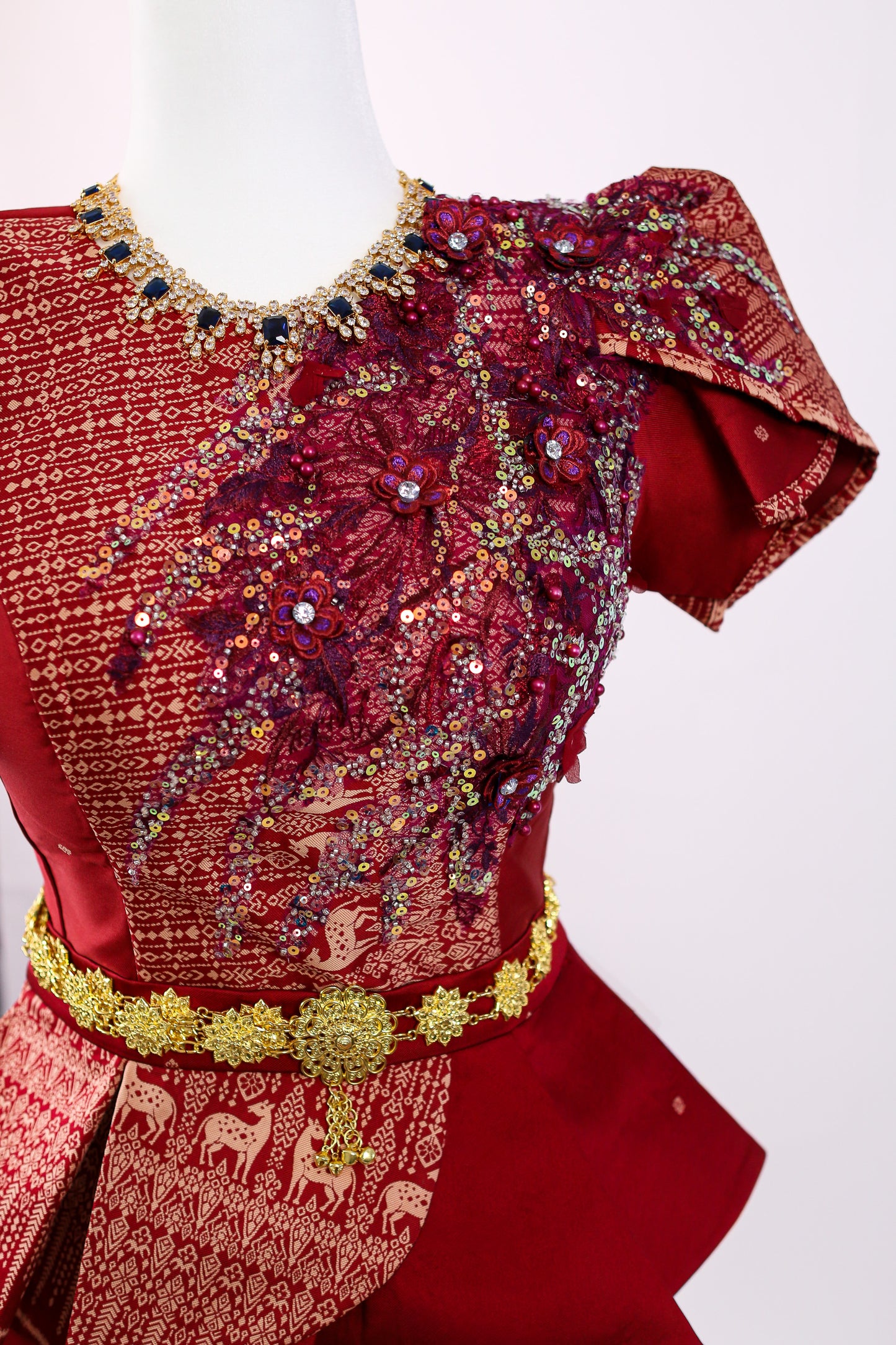 Red embroidered garment on a mannequin with a white background