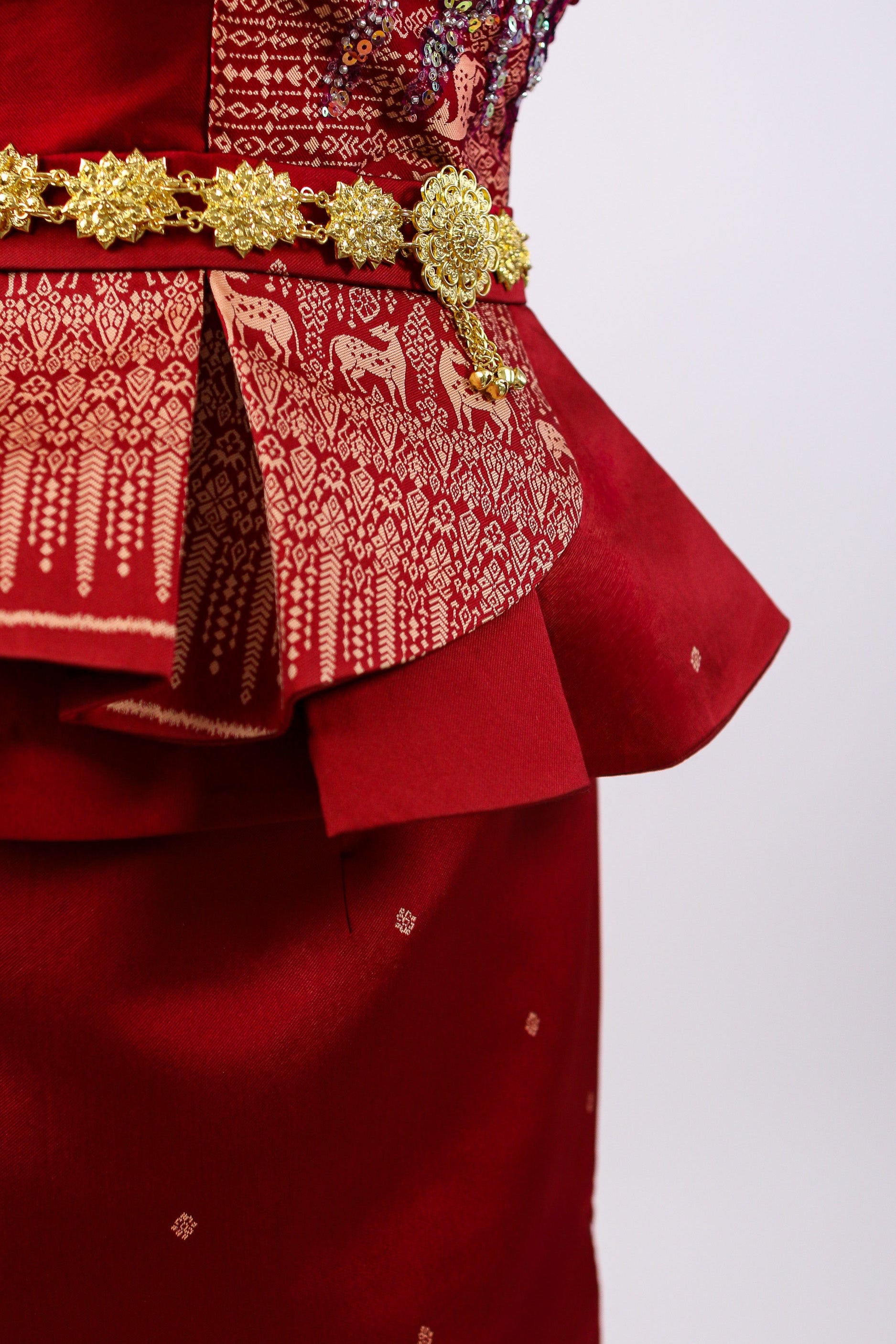 Red traditional outfit with gold embroidery and decorative elements on a white background