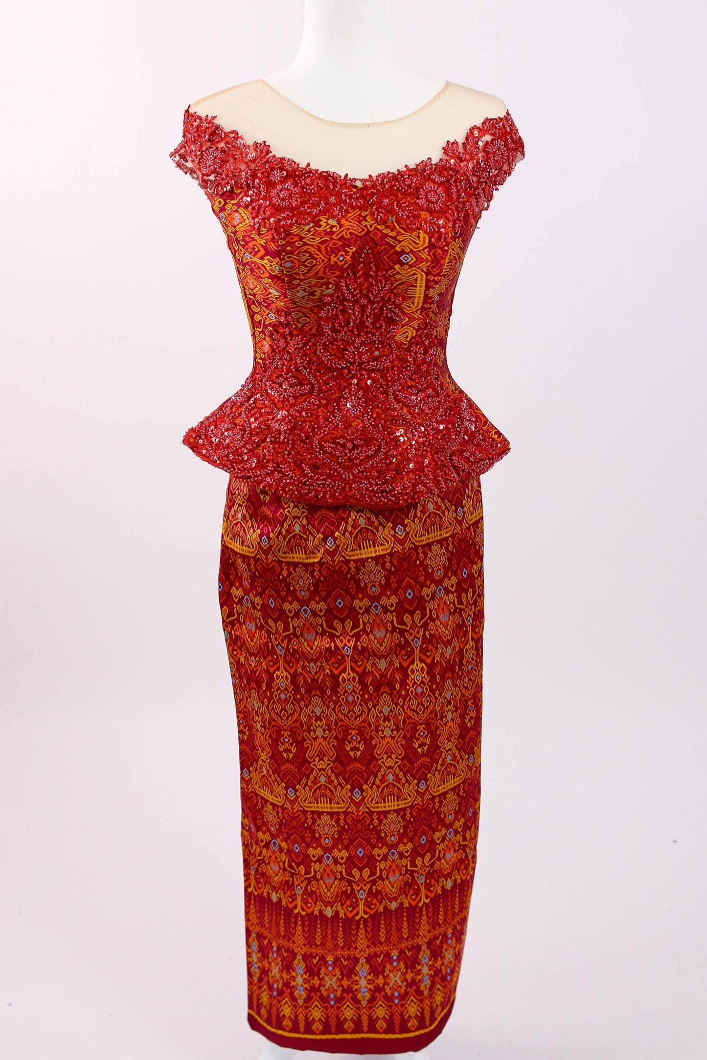 Red and orange patterned dress on a white mannequin against a white background