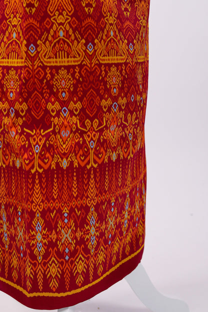Red fabric with intricate orange and blue patterns on a white background