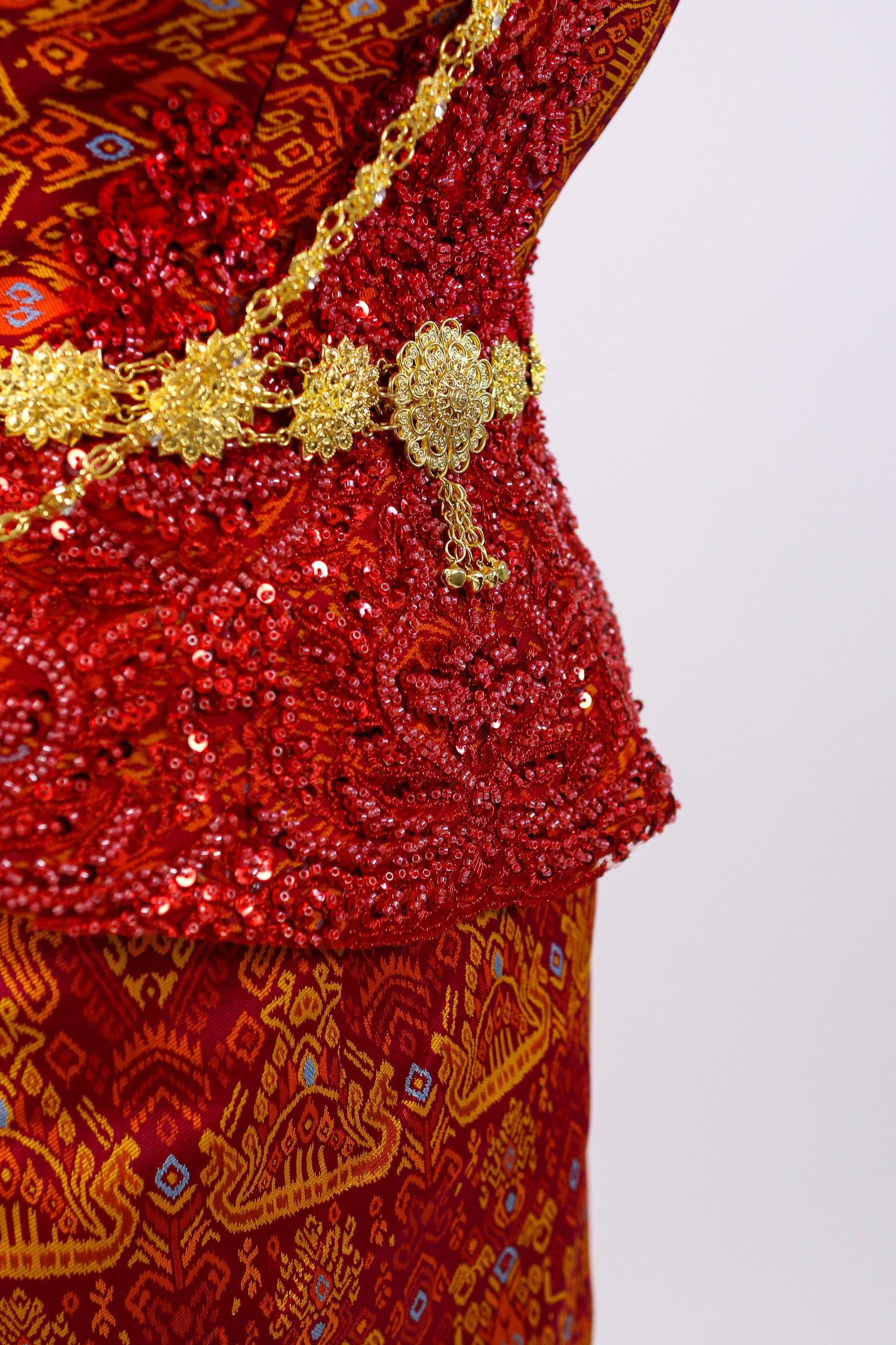 Red embroidered garment with gold detailing on a white background