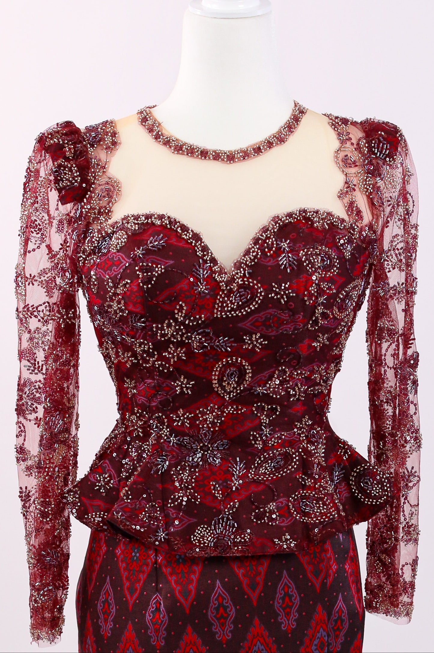 Red lace dress with intricate patterns on a mannequin against a white background