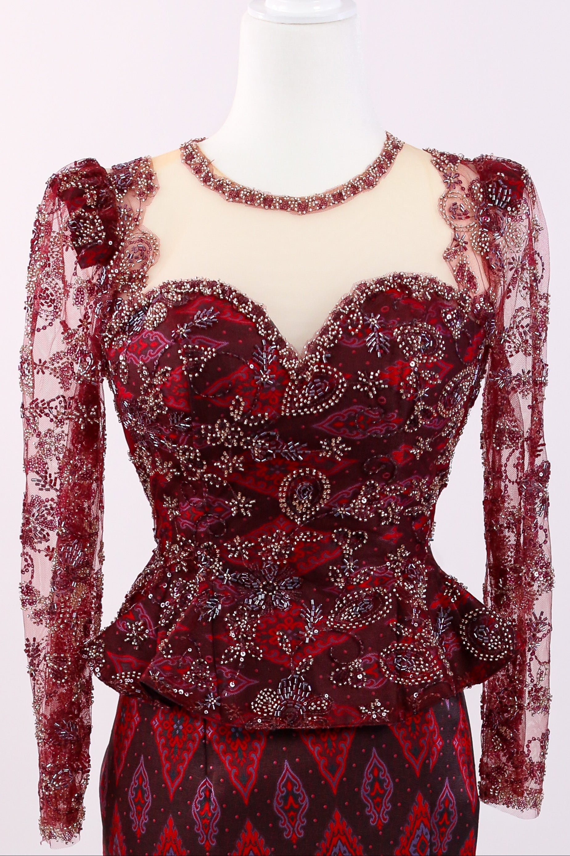Red lace dress with intricate patterns on a mannequin against a white background
